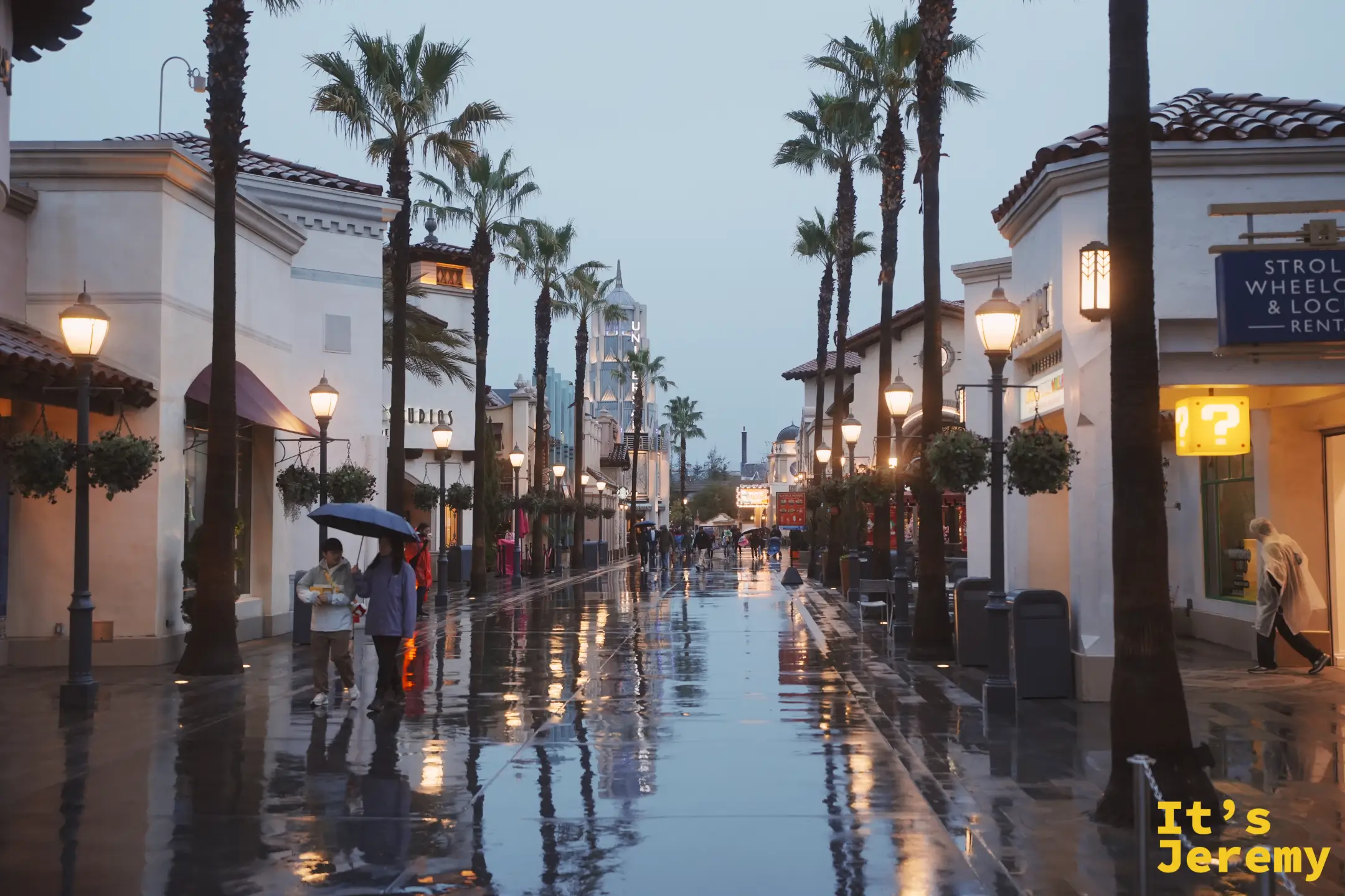 雨後傍晚的 Universal CityWalk 街道，棕櫚夾道、地面反著燈光倒影