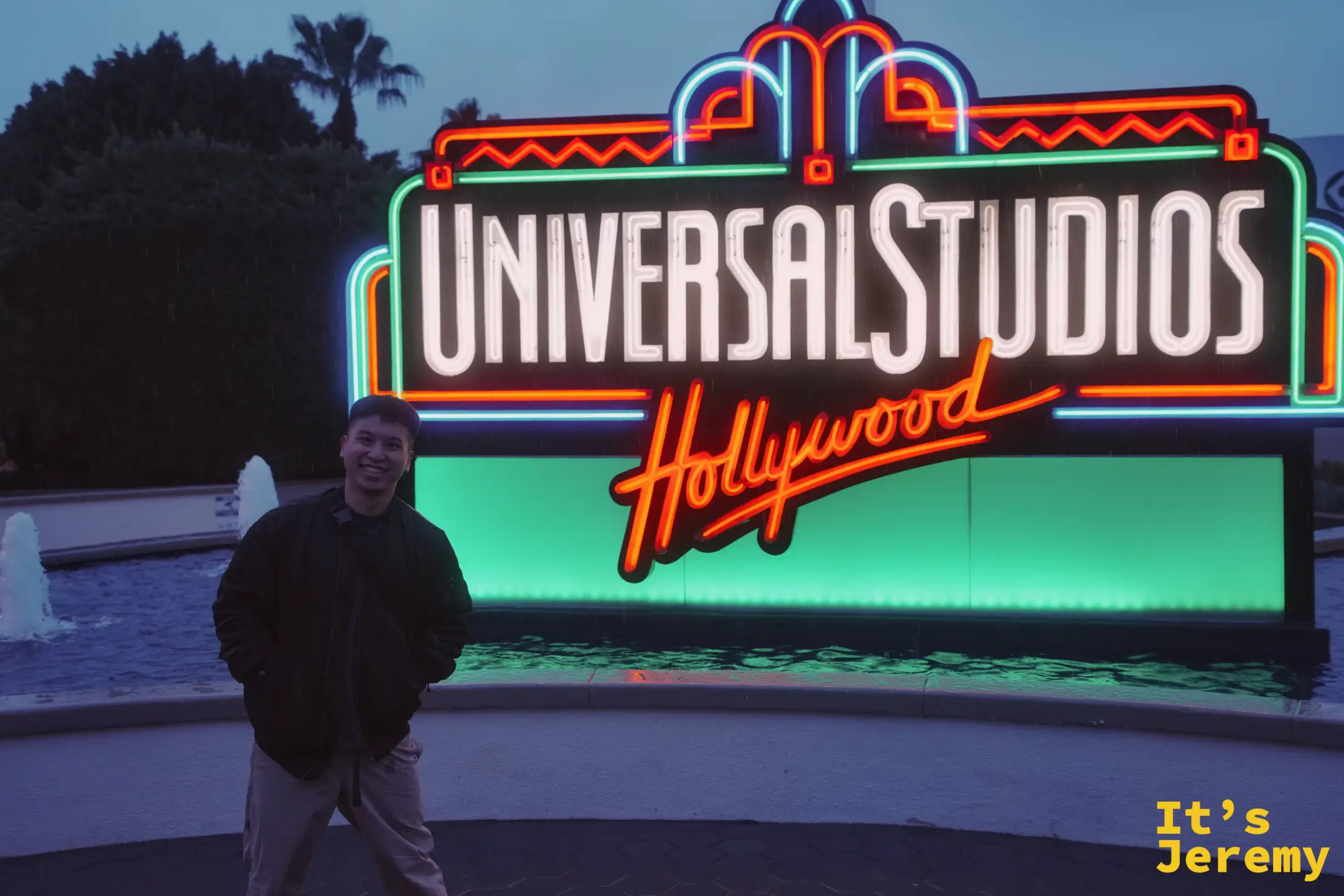 一名遊客站在環球影城 Universal Studios Hollywood 霓虹招牌前，雨後傍晚