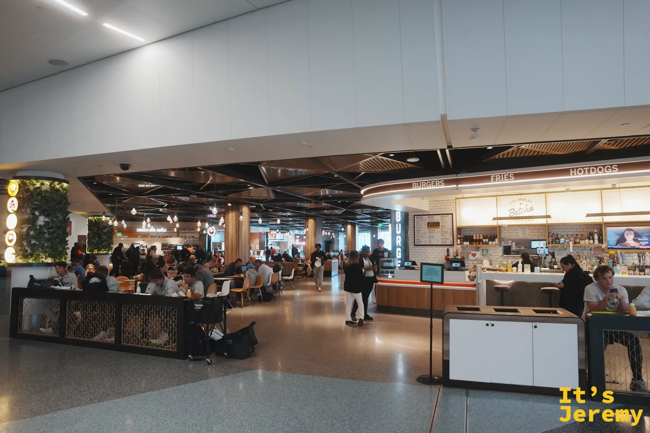 LAX 航廈裡明亮的美食廣場，Betcha 漢堡吧、Einstein Bros Bagels 與 Chick-fil-A 環繞著中央用餐區