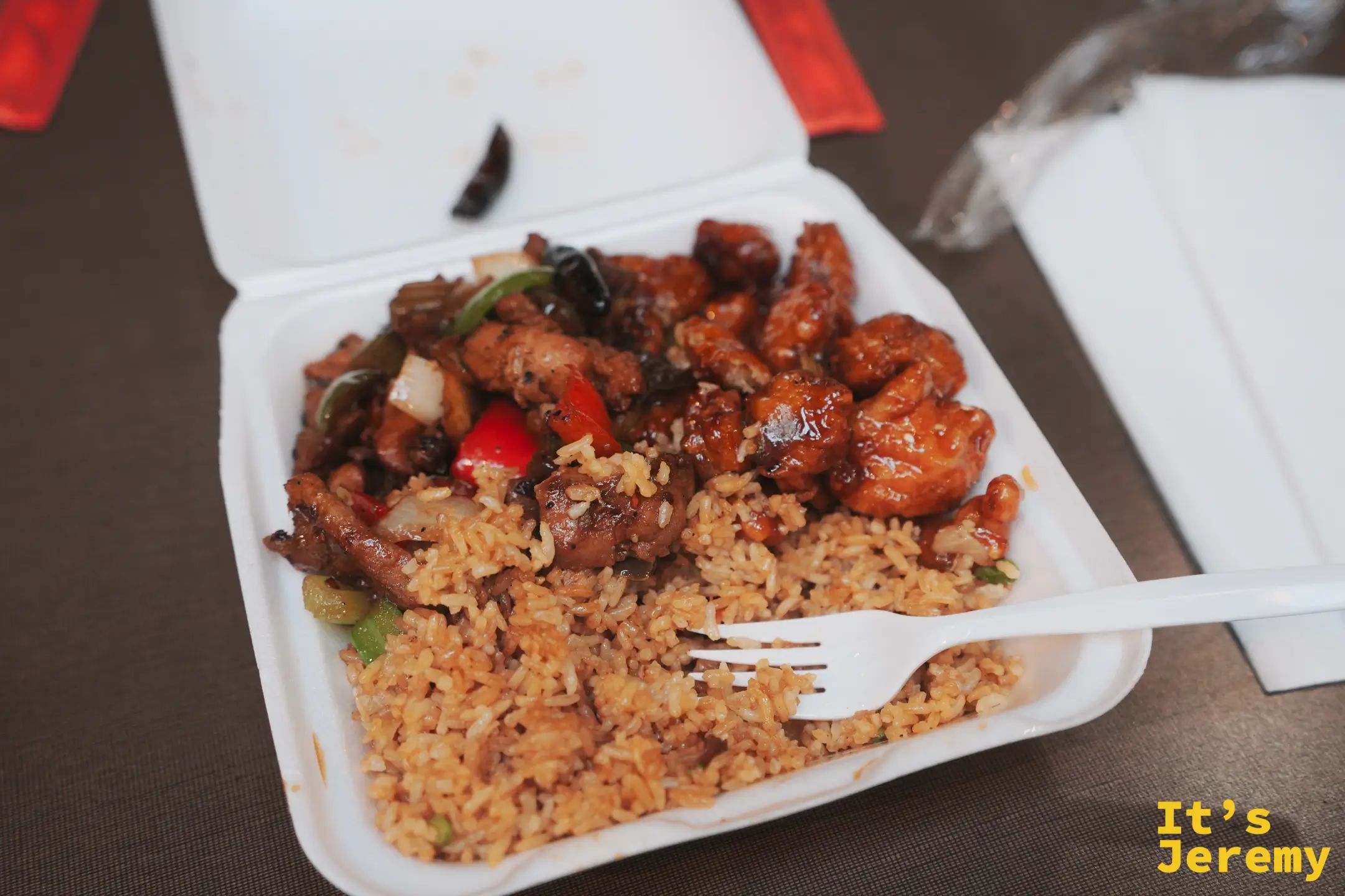 Wok-A-Holic 的餐盒，炒飯上鋪著油亮的橙汁雞與辣椒青椒同炒的宮保雞丁