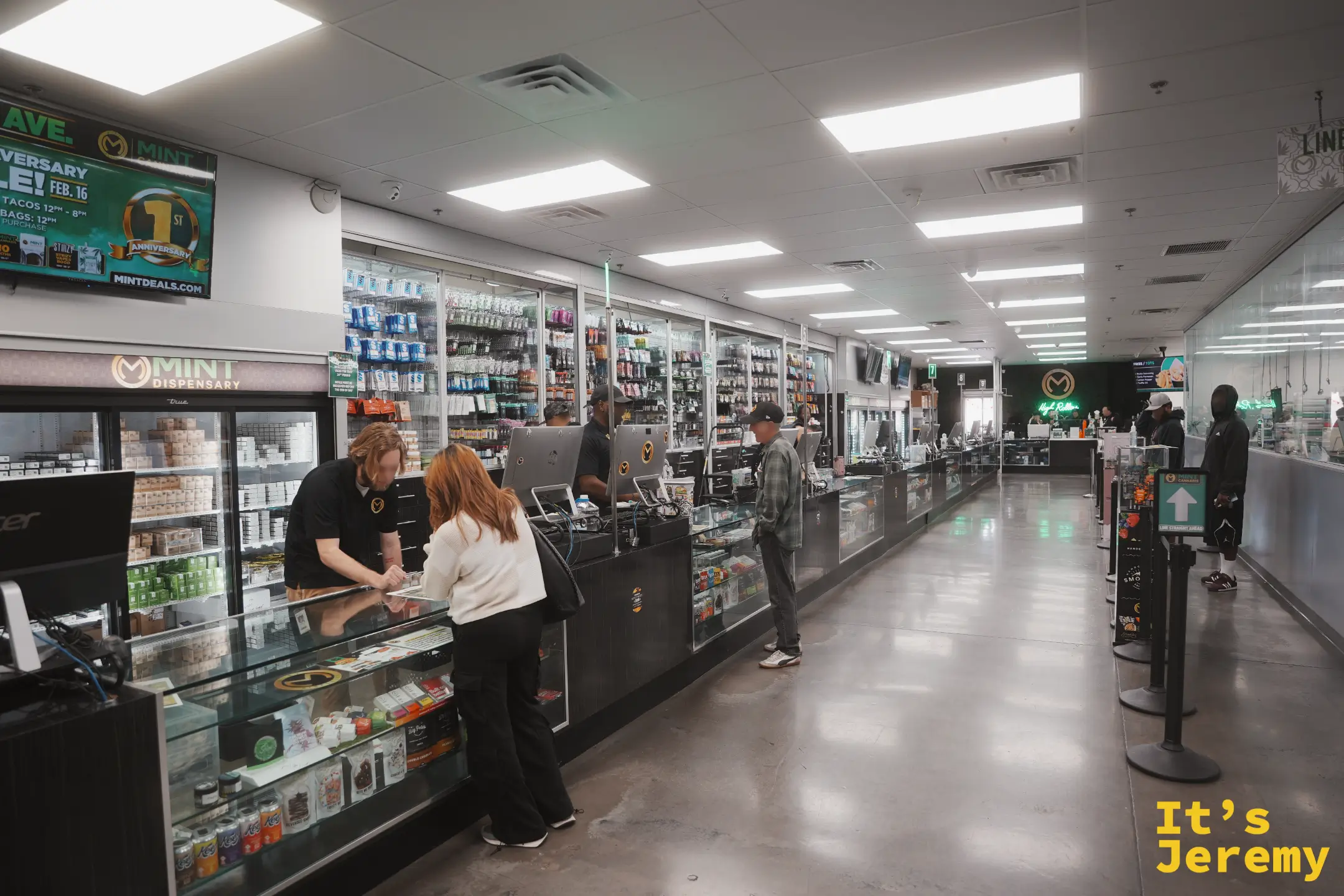 Mint Cannabis 店內的長排玻璃展示櫃與點餐螢幕，店員正在櫃檯後方服務客人