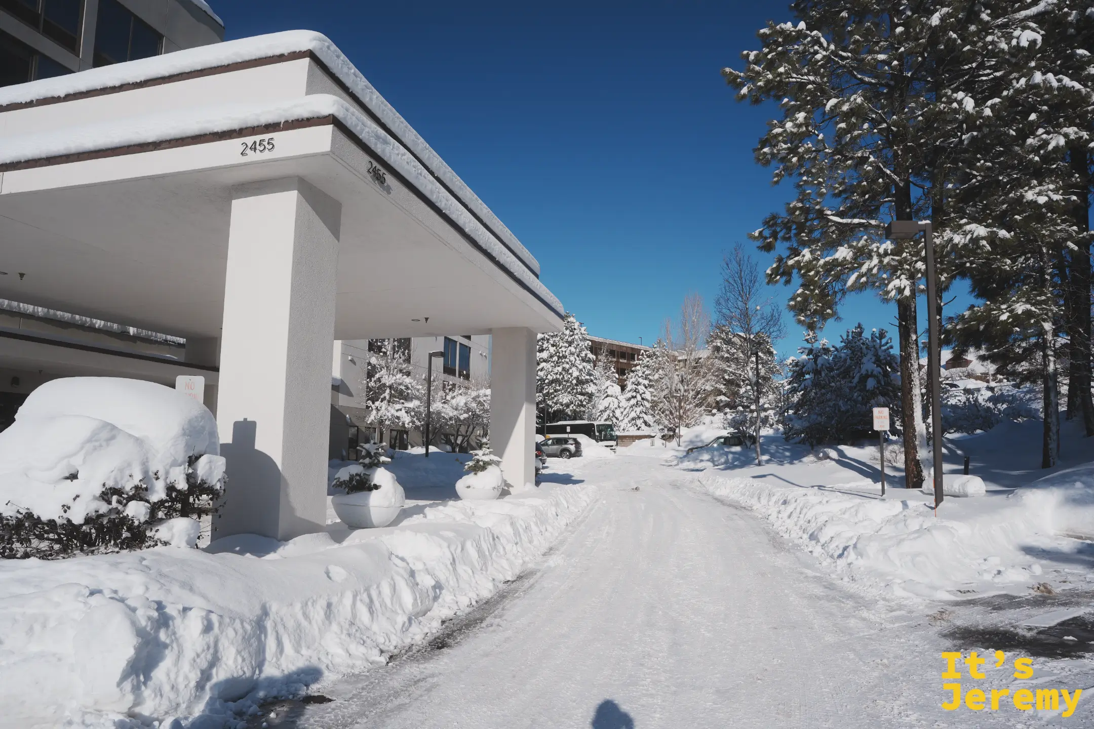 旅館的白色門廊上壓著厚雪，車道被鏟出一條結冰的路，兩旁松樹全被雪蓋住
