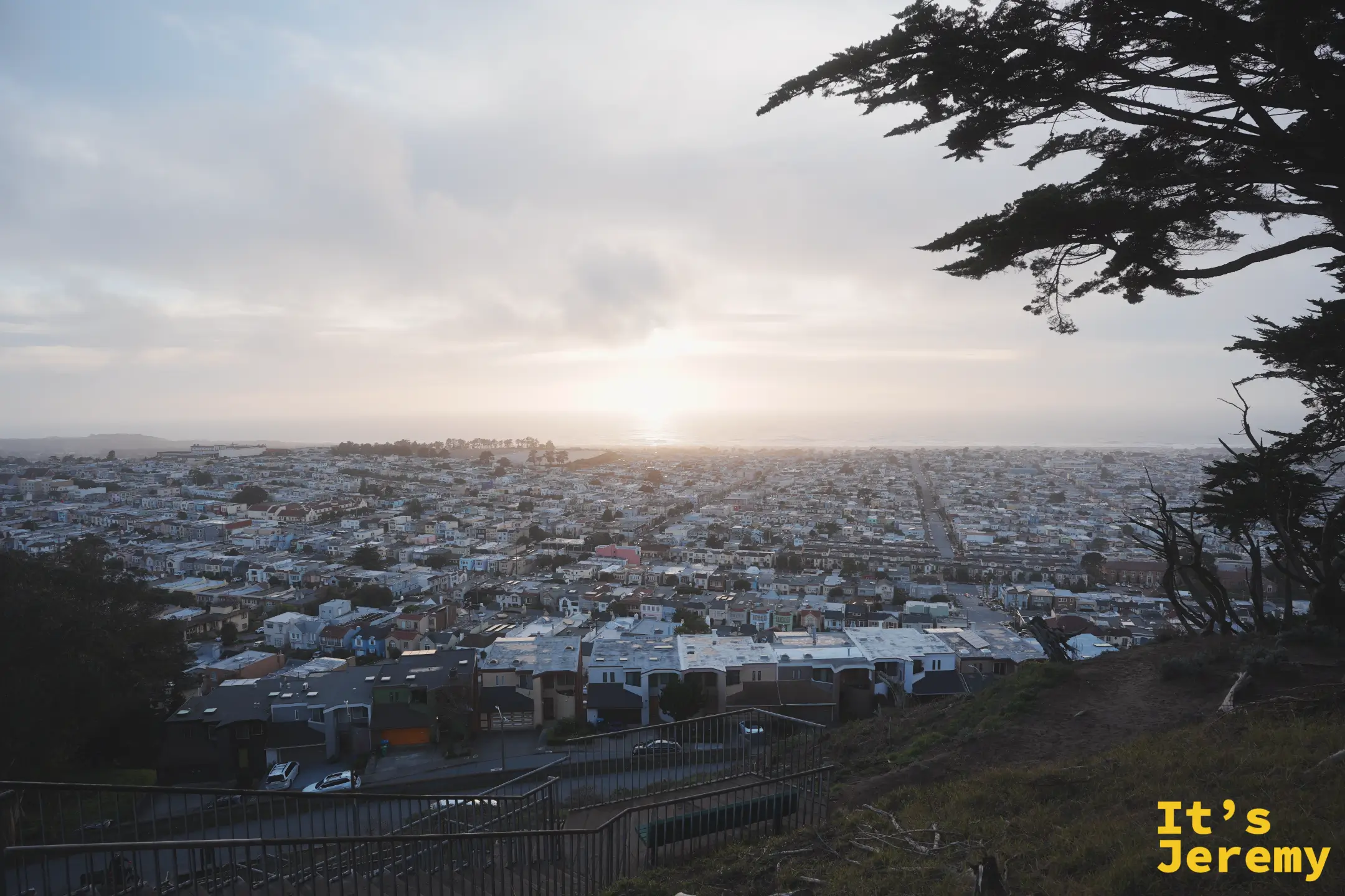 從 Grand View Park 俯瞰日落區，夕陽正沉向太平洋，把整片屋頂染成暖色