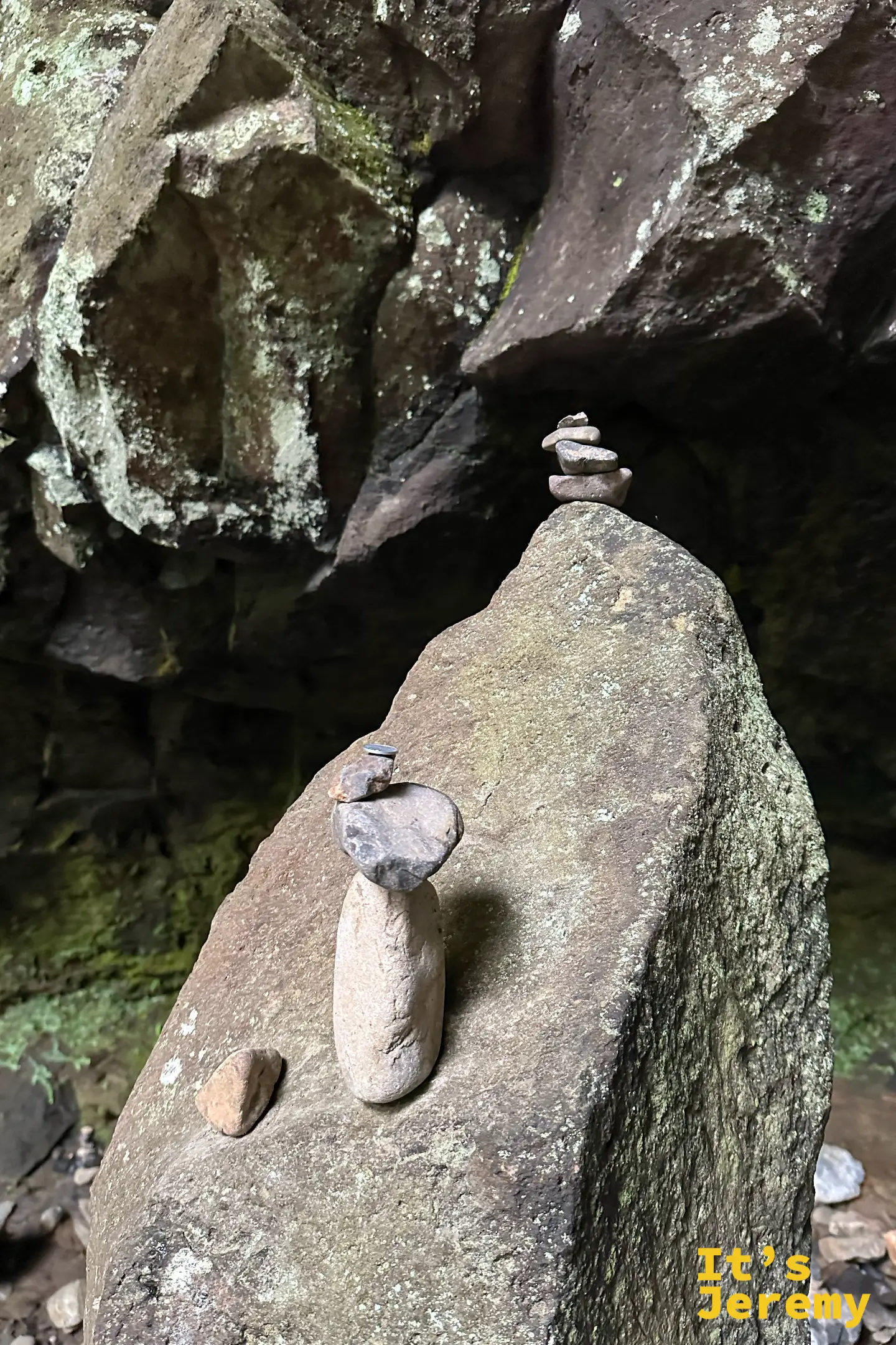 一座只有幾顆溪石疊成的小石塔，立在深色岩石上