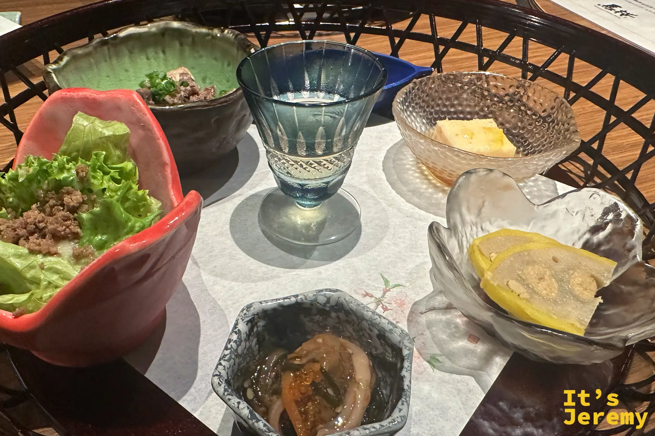 前菜籠盛特寫，生菜包肉燥、醃海味與黃色漬物