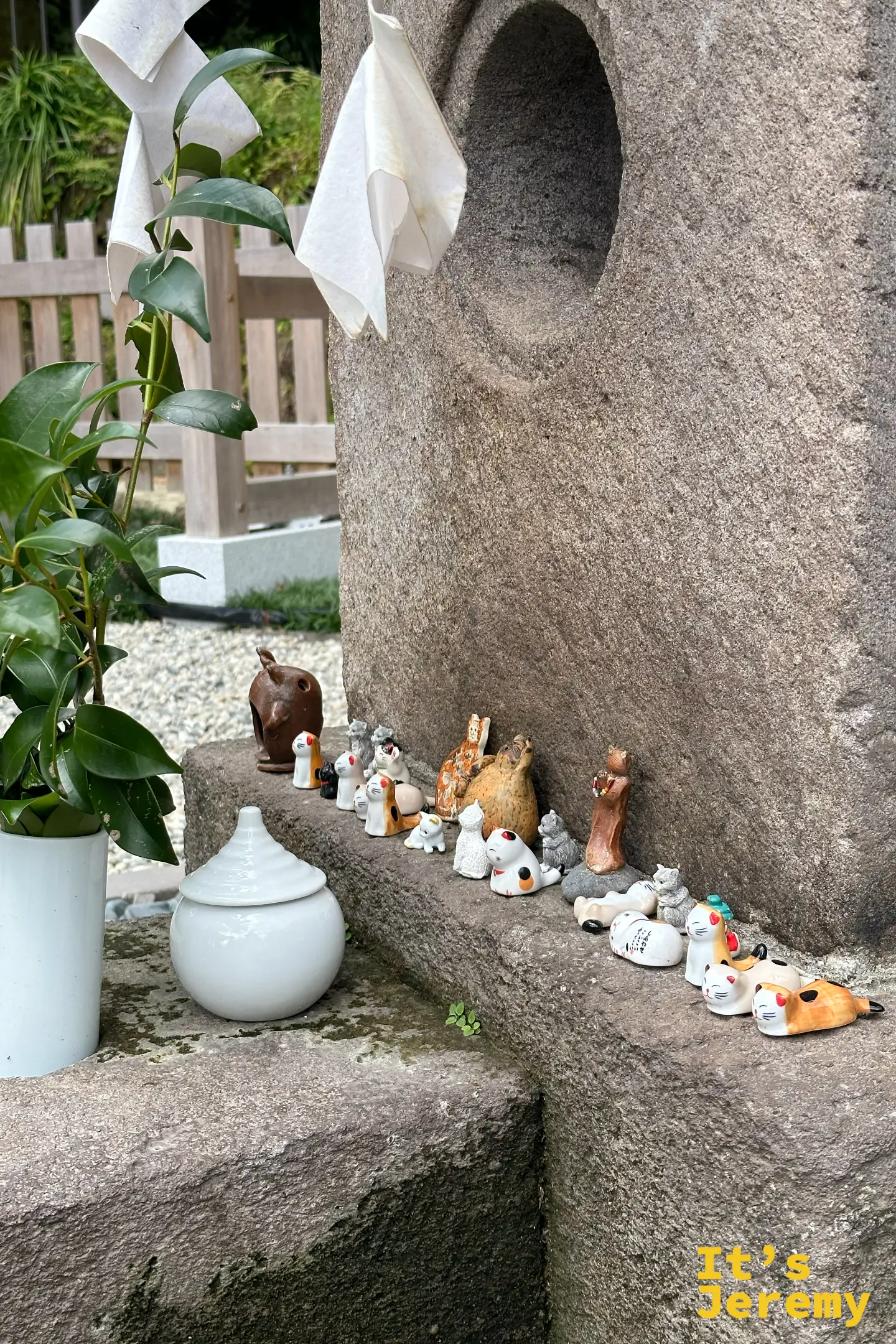 猫神神社的石座前擺滿信眾供奉的小貓陶偶，姿態各異，旁邊立著白瓷淨瓶