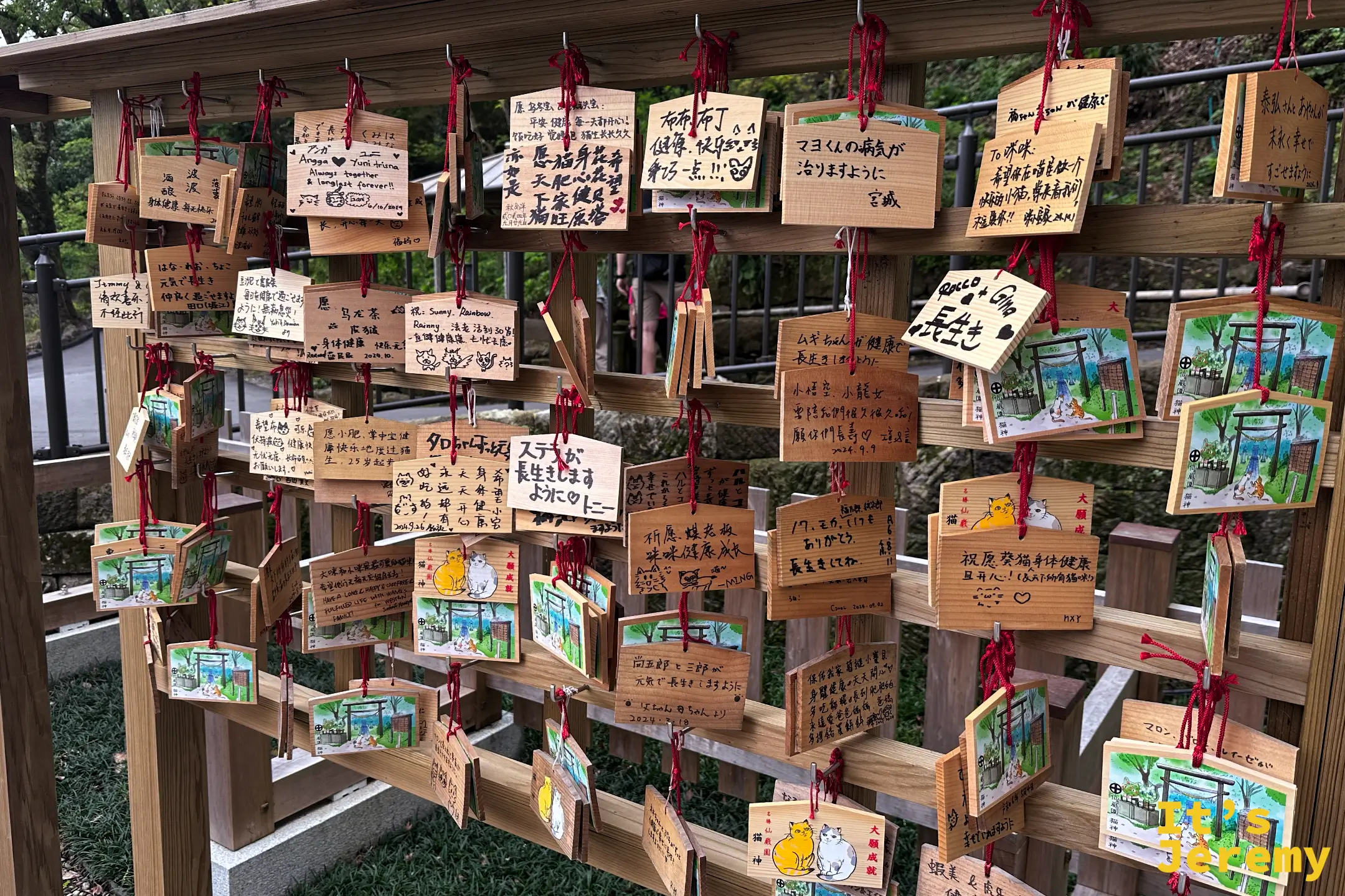 猫神神社旁的繪馬牆，一整排木製祈願牌上畫著各種貓咪，用中日英文寫著替自家貓咪祈求健康長壽的願望