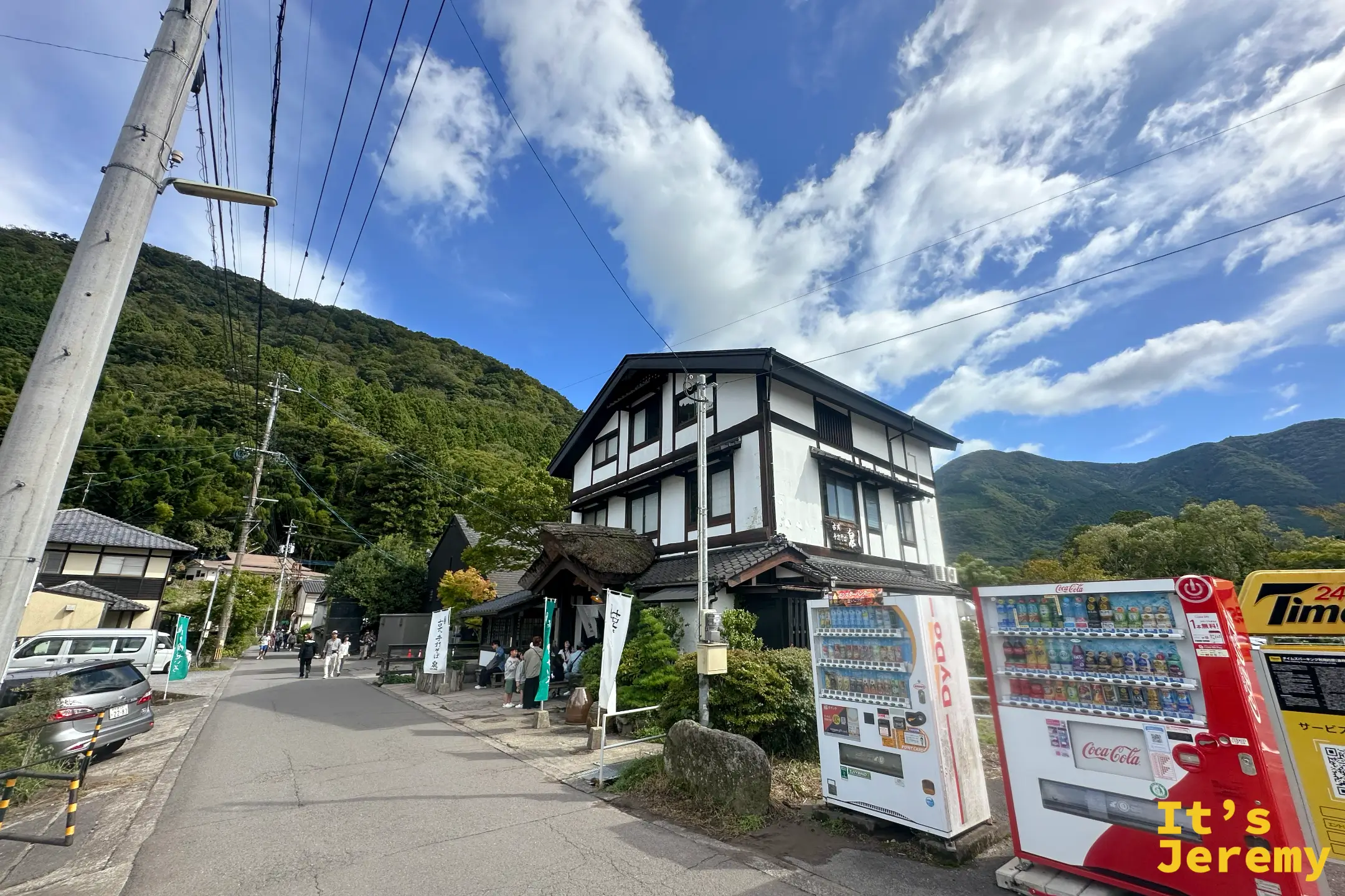 古式手打ちそば 泉的三層木造老屋遠景，撐在金鱗湖畔的山腳下，藍天白雲
