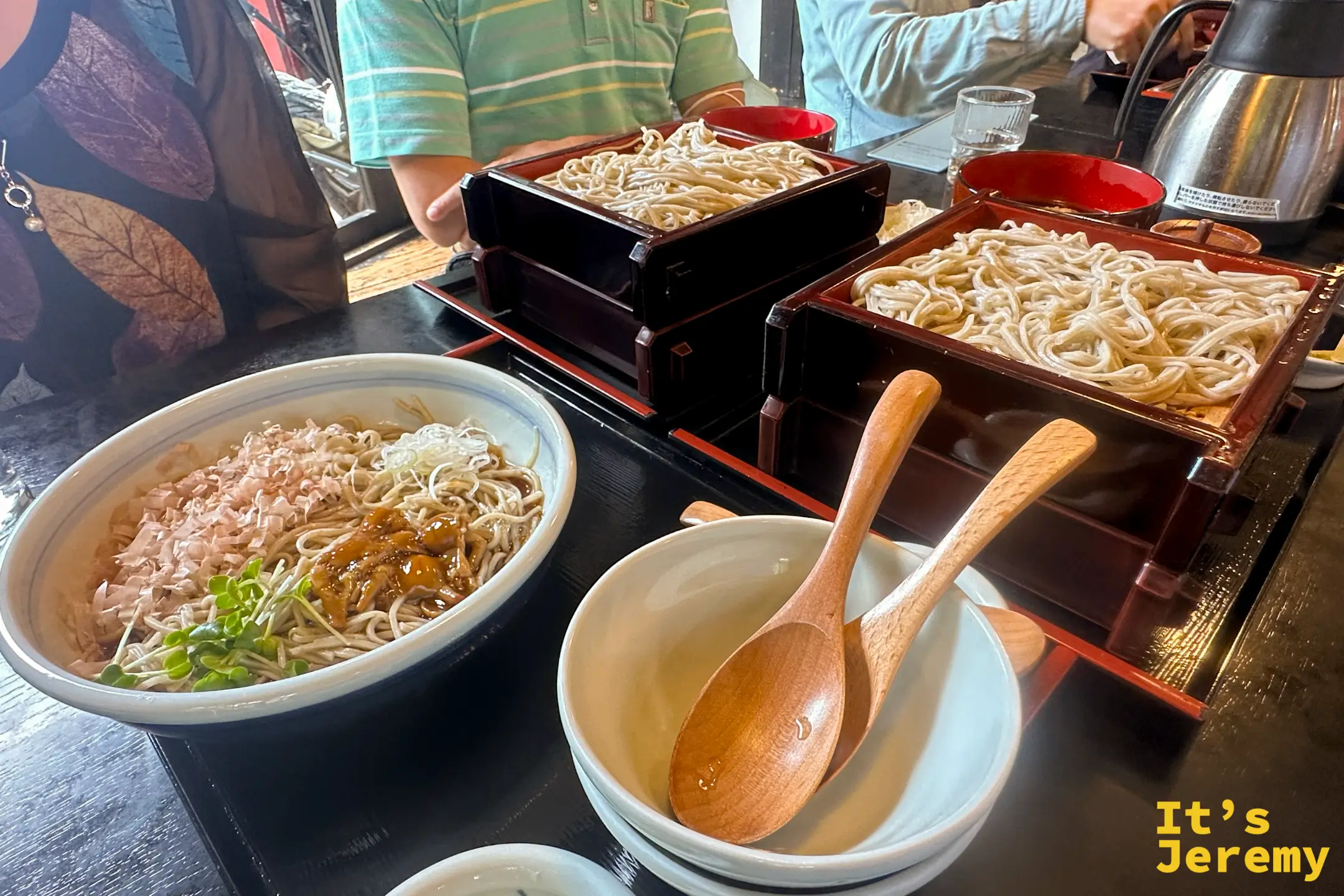 泉的桌上兩份蒸籠蕎麥並排，前方一碗柴魚冷蕎麥附木湯匙與保溫壺