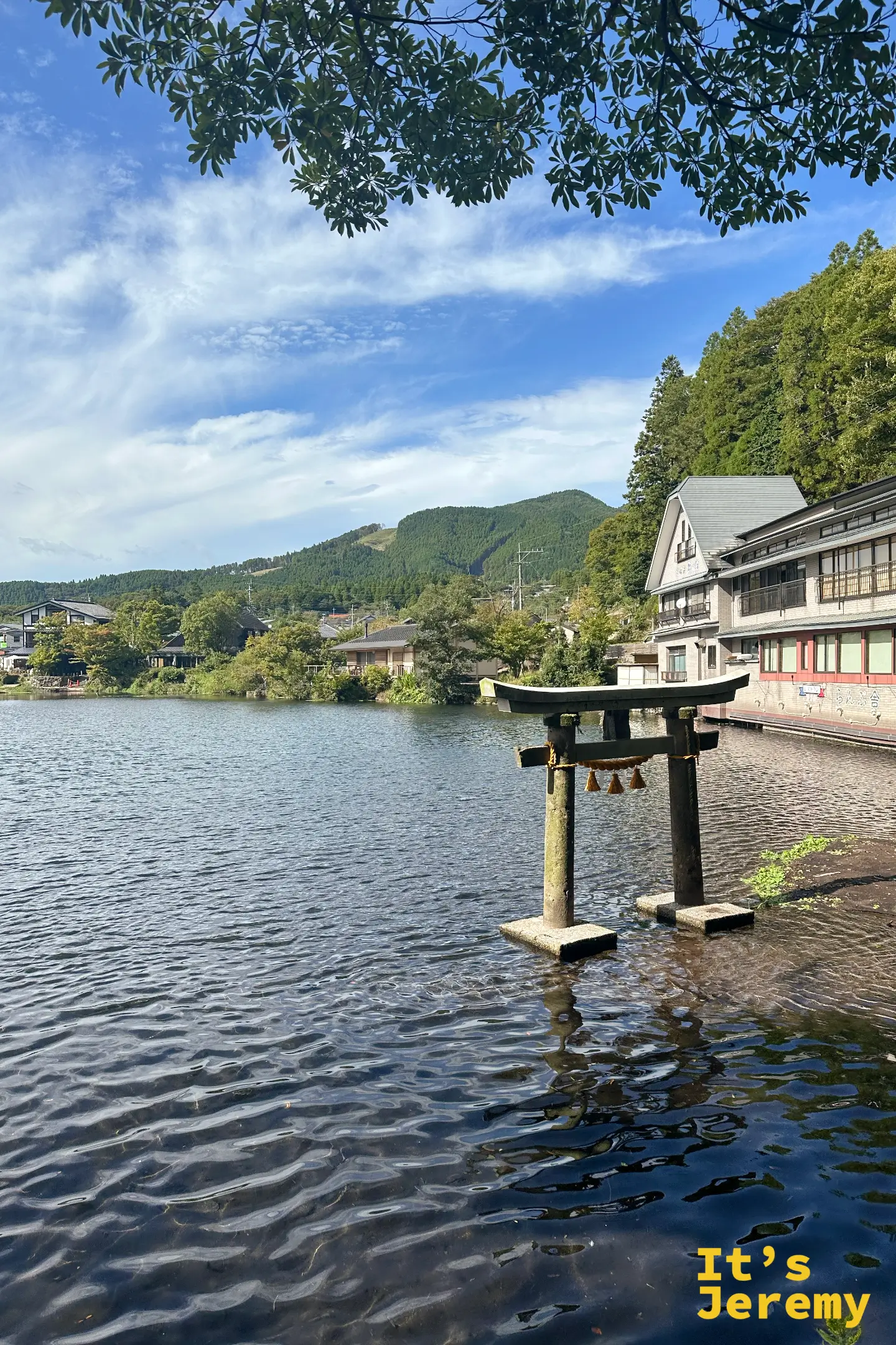 立在金鱗湖水中的石鳥居，湖畔有粉色建築