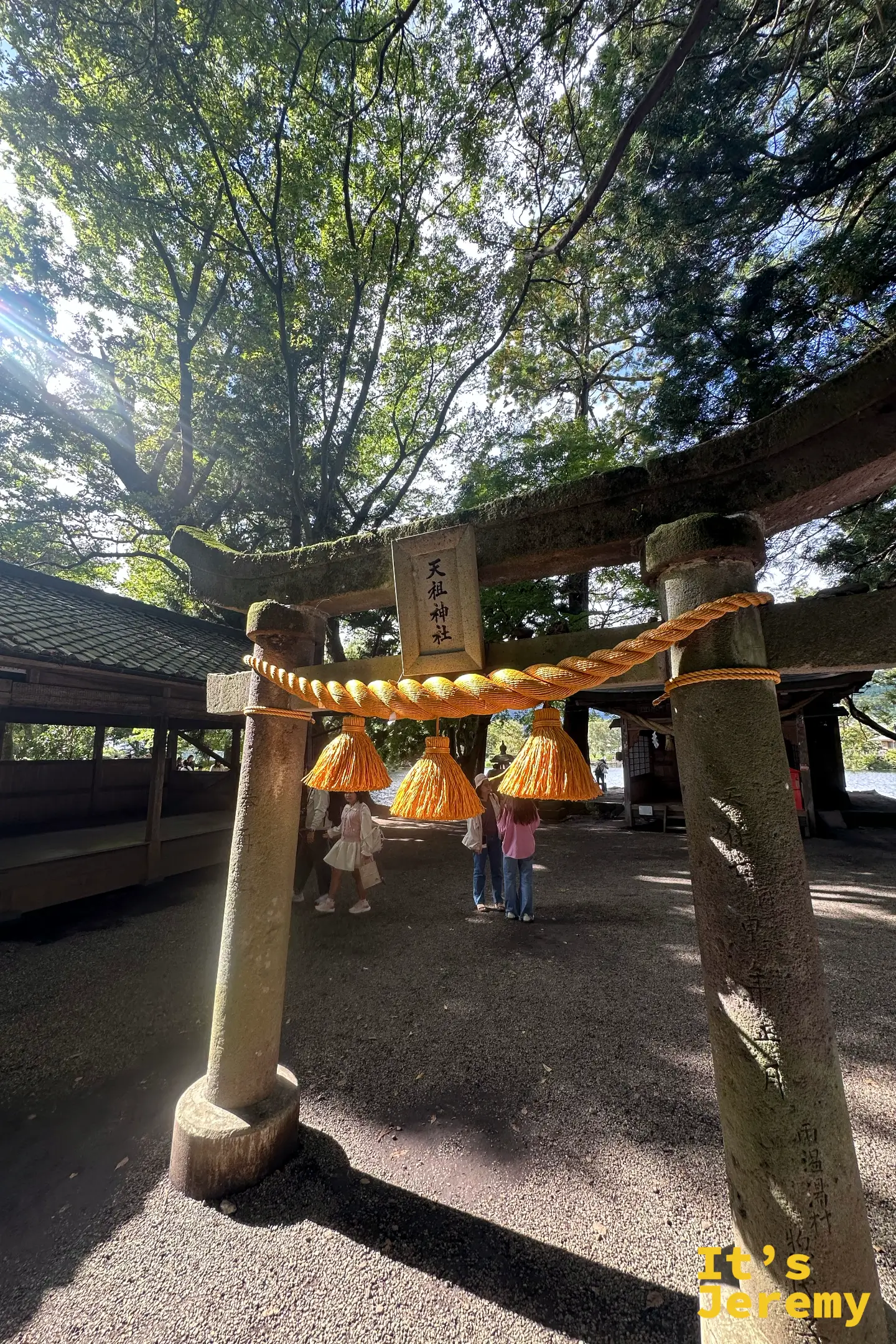 天祖神社的石鳥居仰角，橙黃色注連繩垂著三束稻穗穗飾，扁額寫著天祖神社