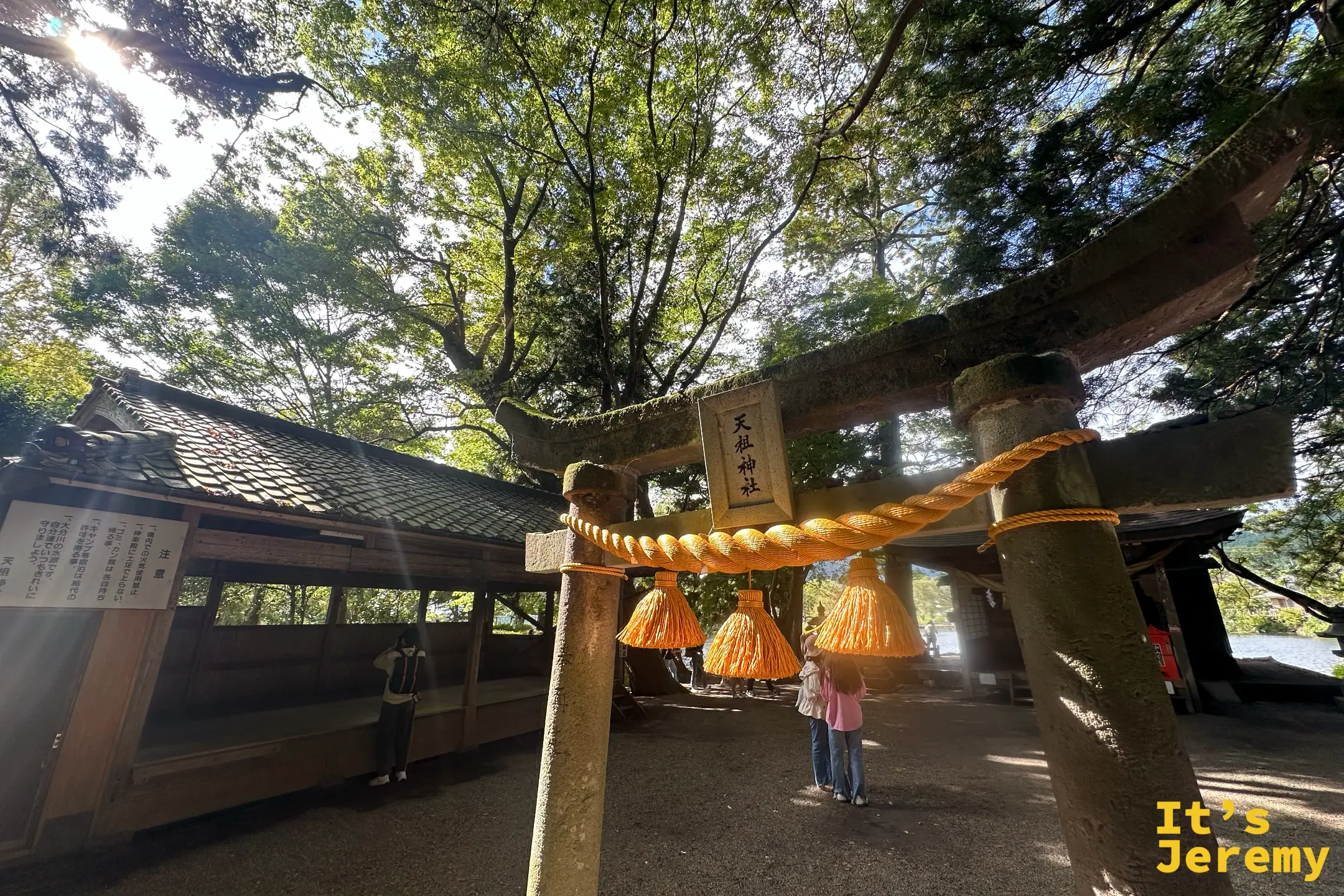天祖神社石鳥居全景，左側為木造拜殿，遊客在境內走動
