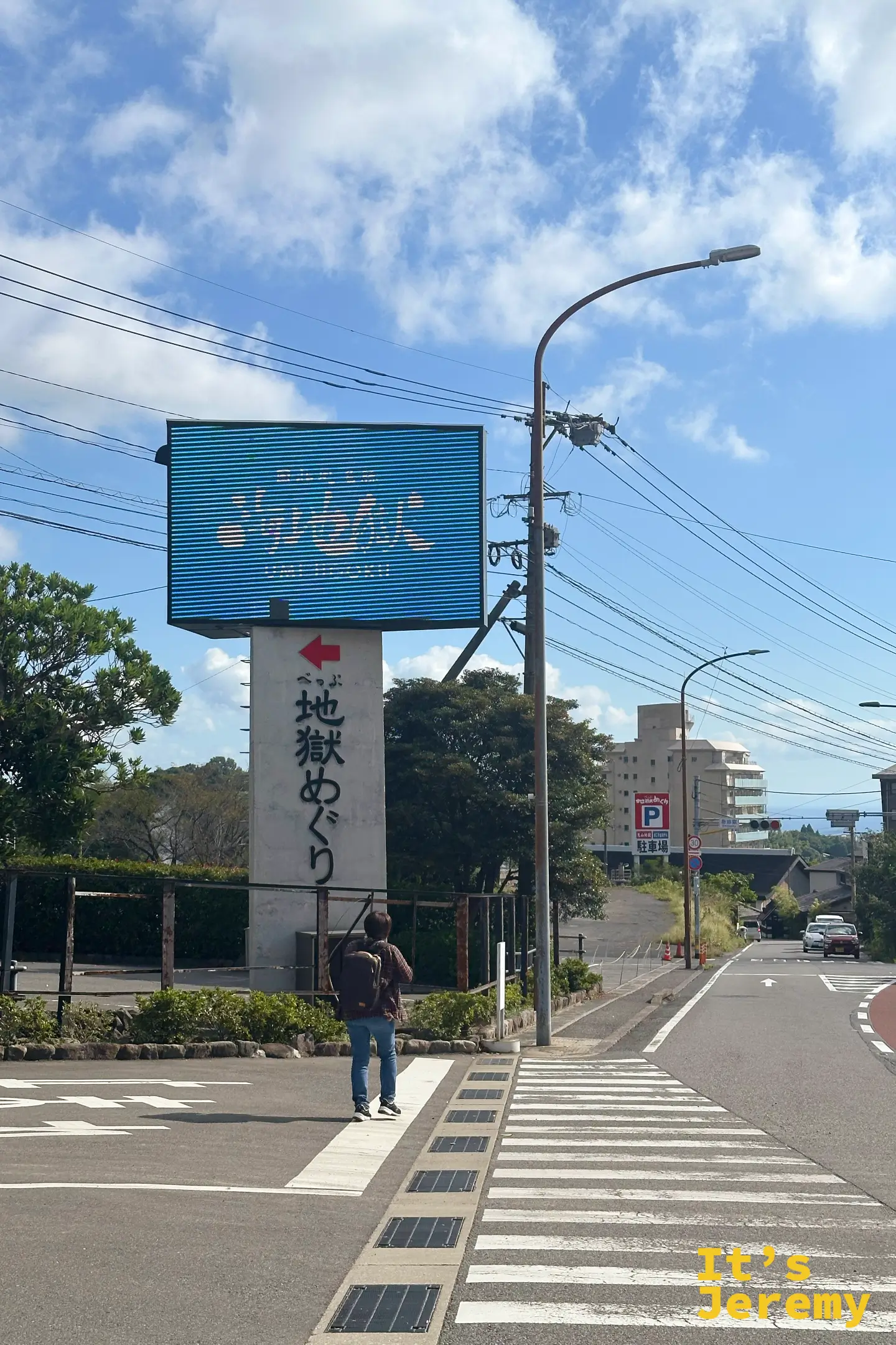 路邊的藍色 LED 電子看板寫著「べっぷ地獄めぐり 海地獄」，紅色箭頭指向停車場