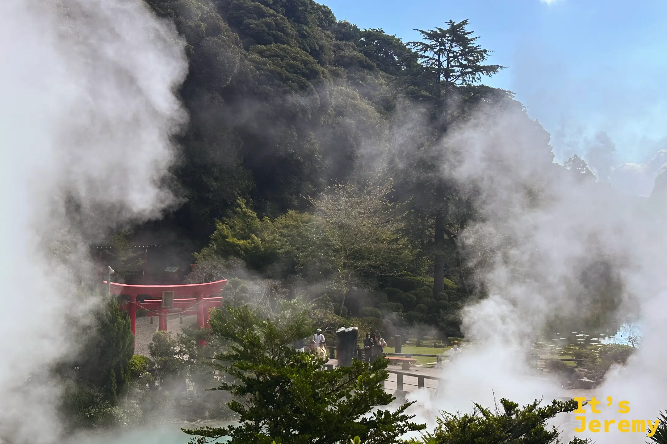 蒸氣中的紅鳥居與遊客，背後是綠色山壁與藍天