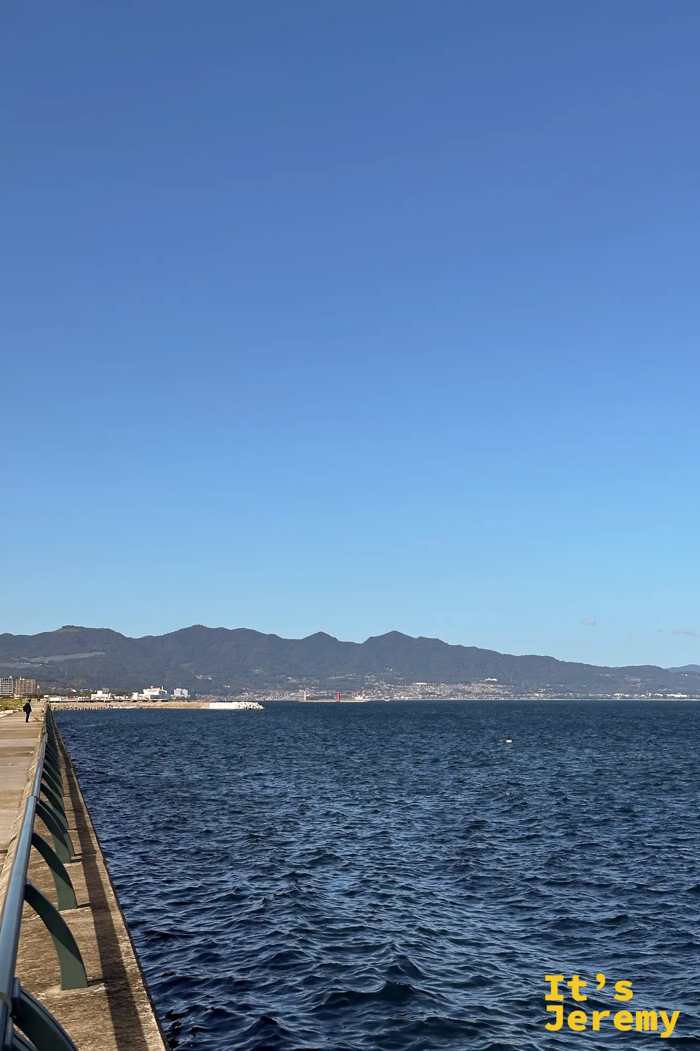 站在別府灣的防波堤上，對岸的山稜線橫在海的另一頭