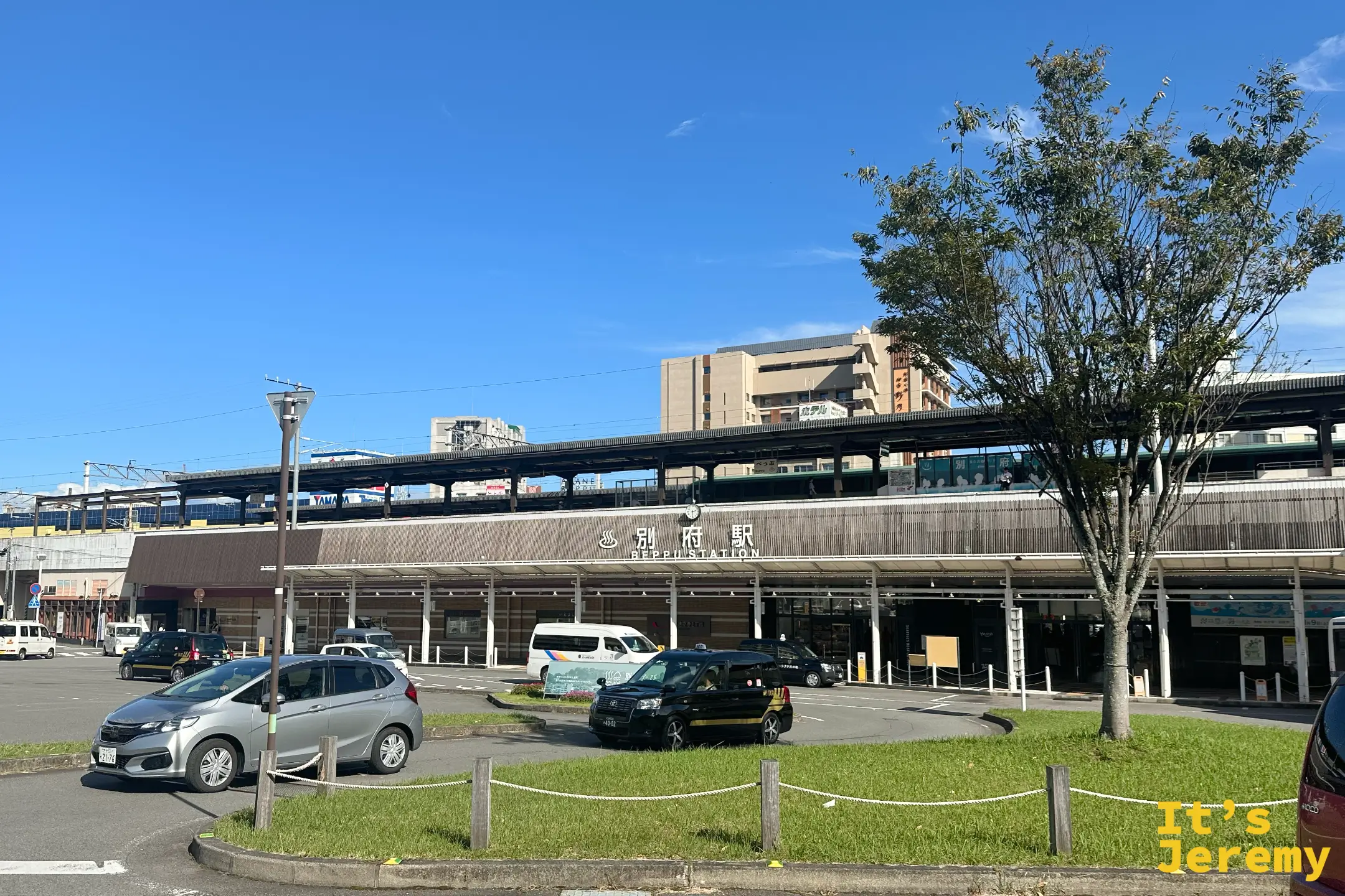 別府車站站前廣場與圓環，低矮的站體橫在後方，前方停著幾輛車