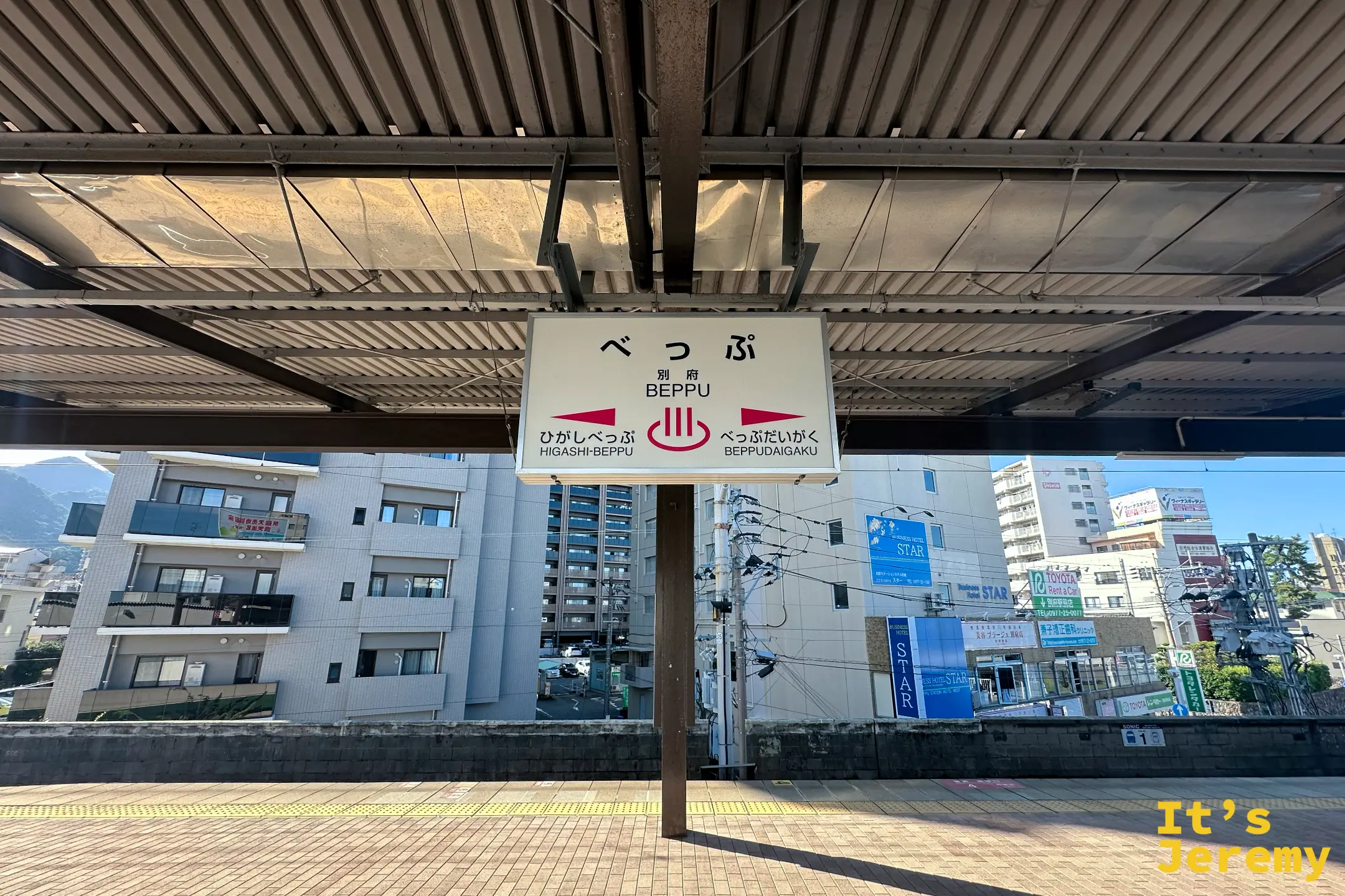 別府車站月台上方掛著「べっぷ BEPPU」的站名牌，兩側標著東別府與別府大學方向