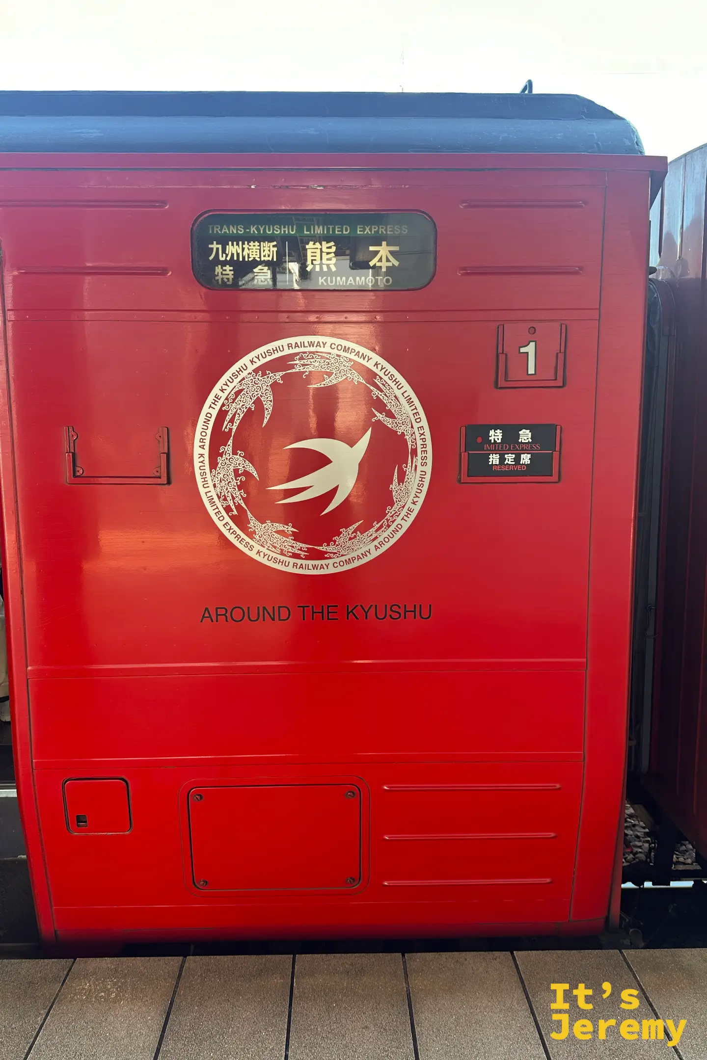紅色特急列車的車門上，白色仙鶴標誌與「熊本」行先，寫著九州横断特急