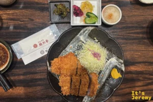 勝烈亭的招牌厚切炸豬排，炸衣蓬得像雪花，一旁附高麗菜絲、黃芥末與現磨芝麻醬碗
