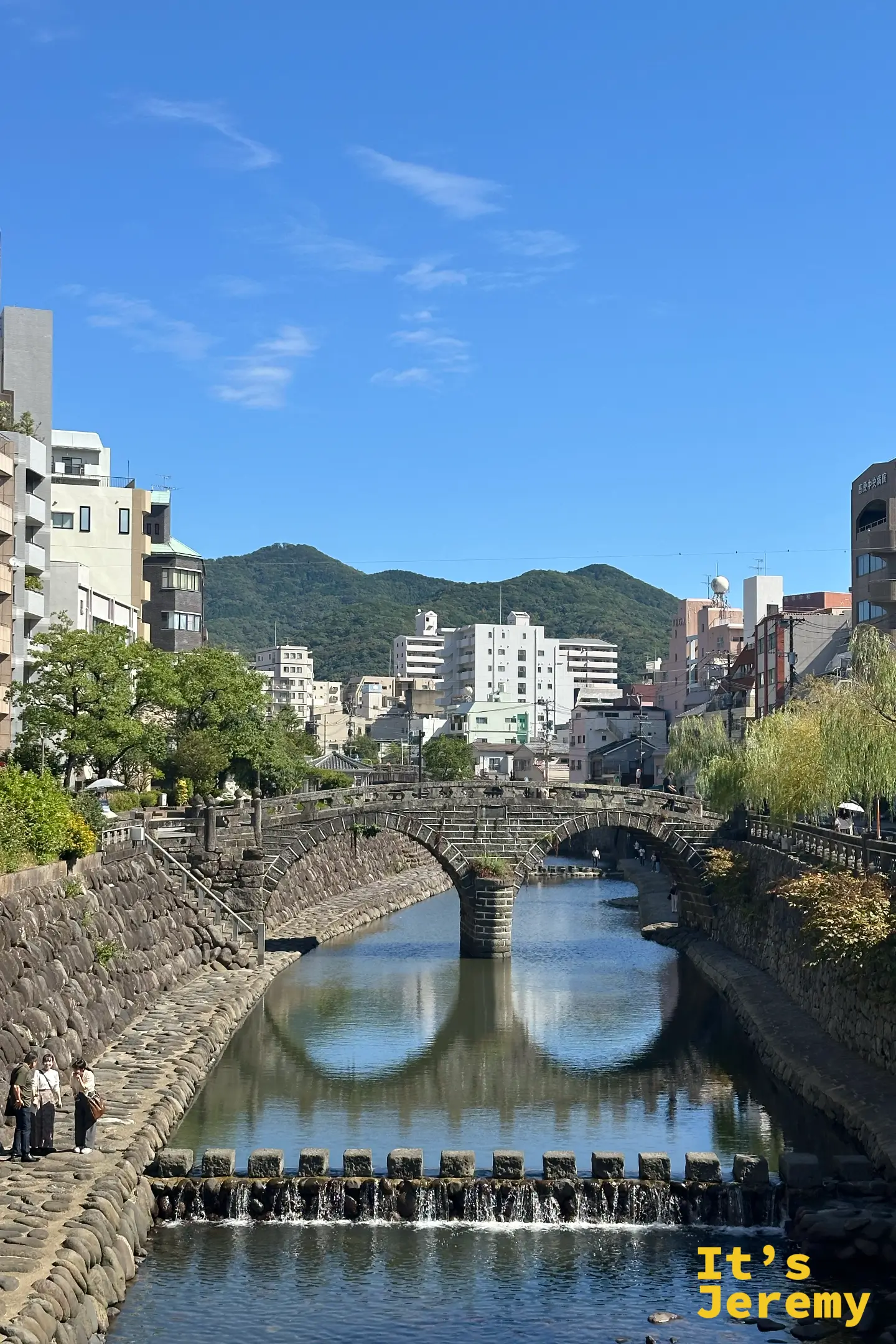 站在中島川河床的方形踏石上，回望眼鏡橋與兩岸柳樹