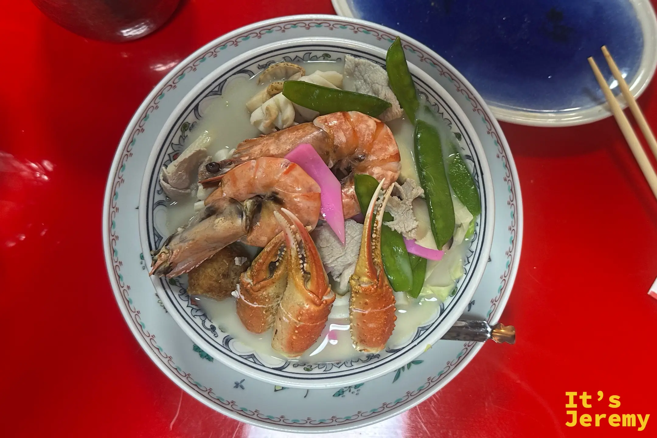 從上方俯看強棒麵，蝦、蟹螯、魚板與蔬菜鋪滿整碗