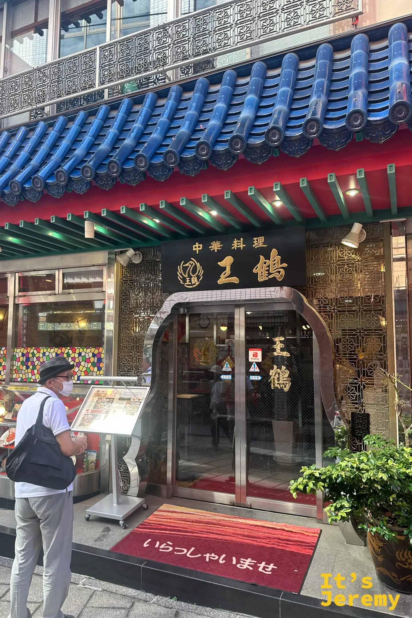 王鶴店門口，藍色屋瓦與黑底招牌，門口立著菜單