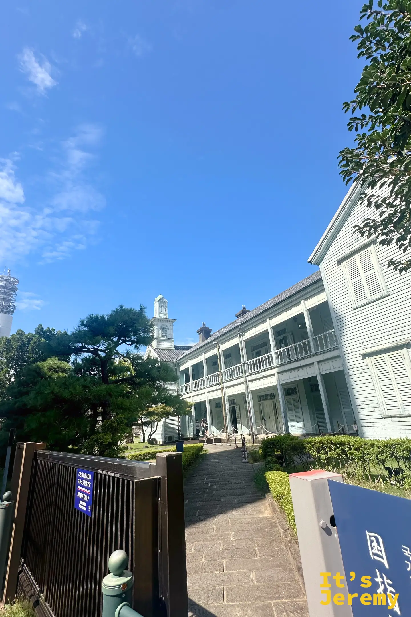 從出島外的石階往上望，西洋二層建築、日式黑瓦與一棵蒼勁的松樹並置