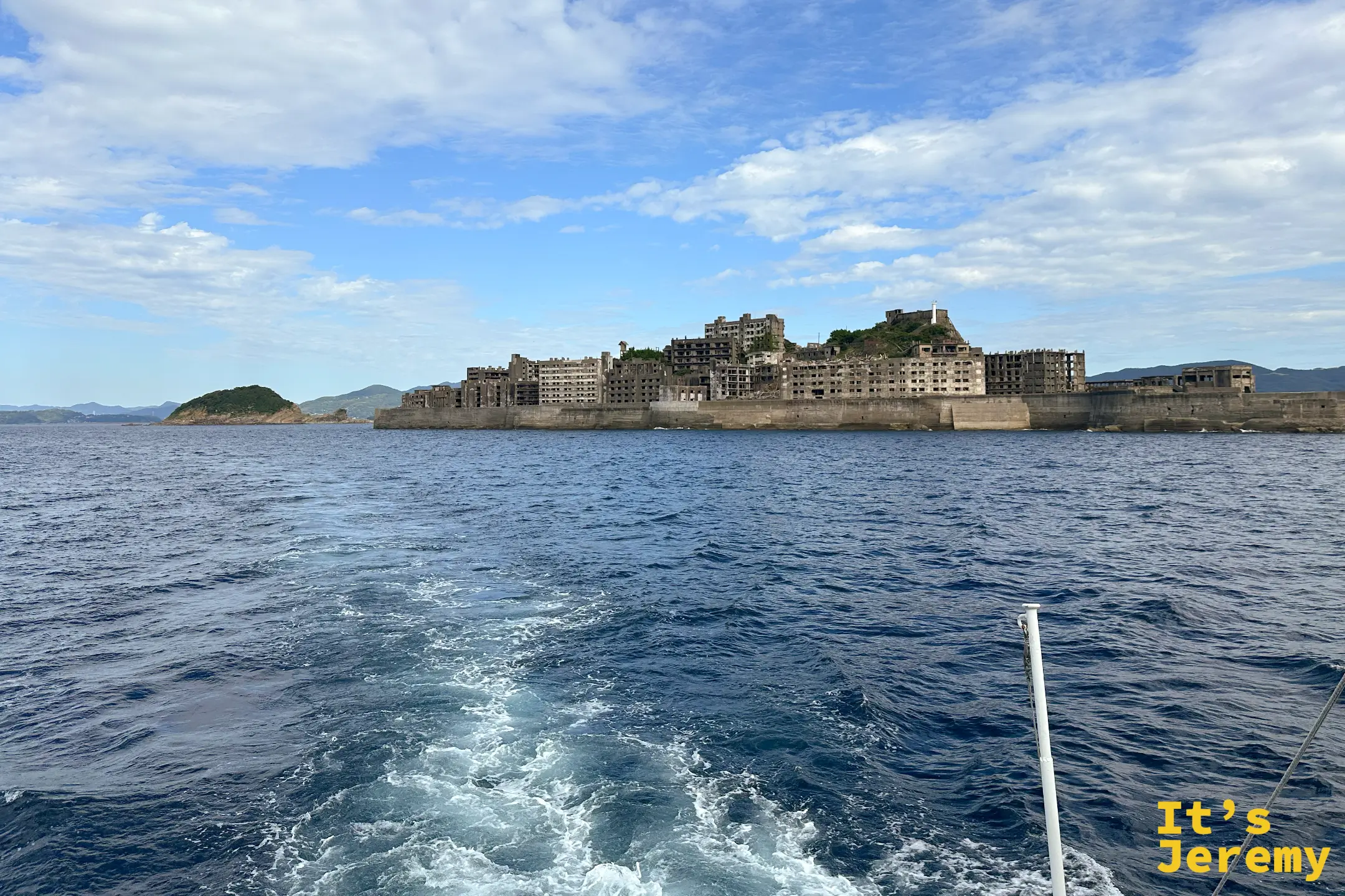 海上近距離看軍艦島綿延的護岸與成排廢棄建築