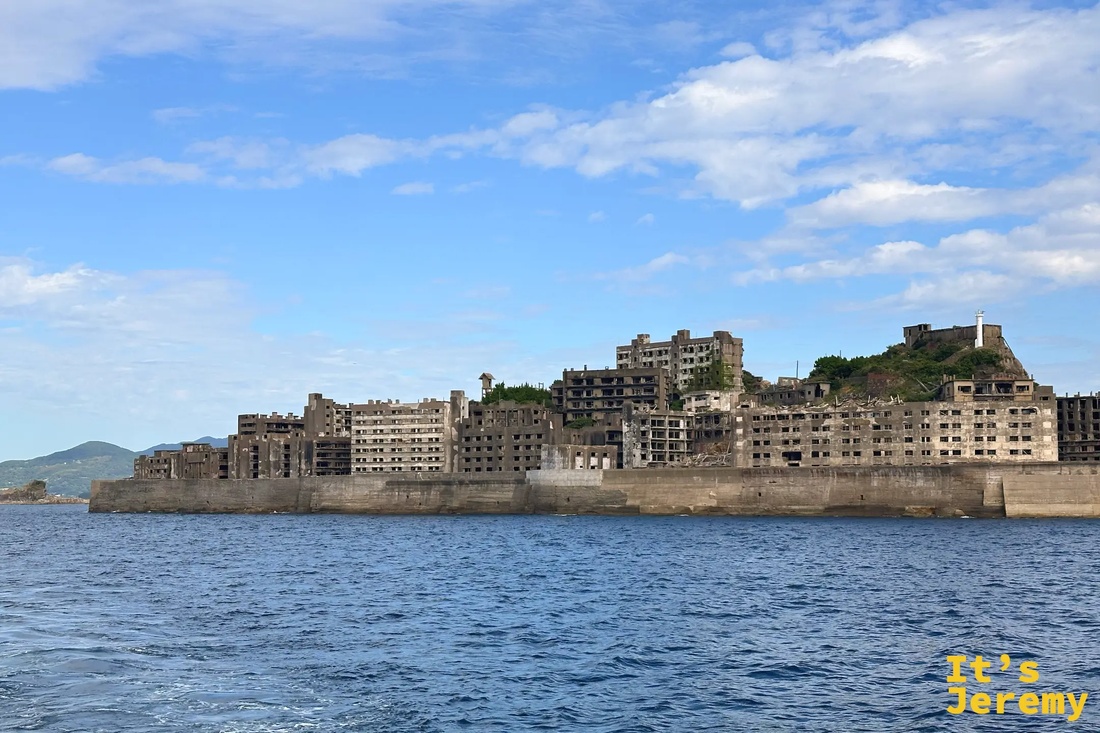 海上另一角度看軍艦島，密集的高層公寓群沿著海岸線排列