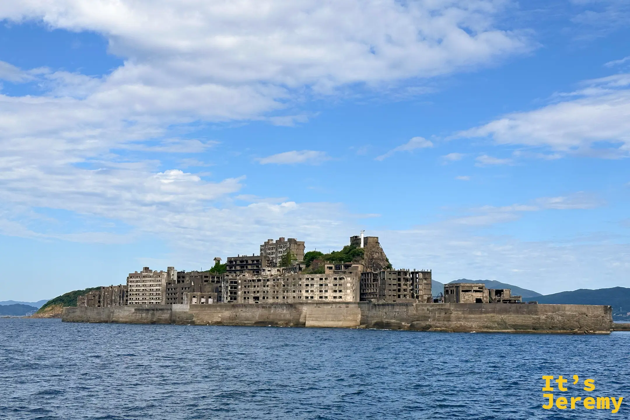 海上看軍艦島，斑駁的水泥廢墟與海天相接，畫面蒼涼