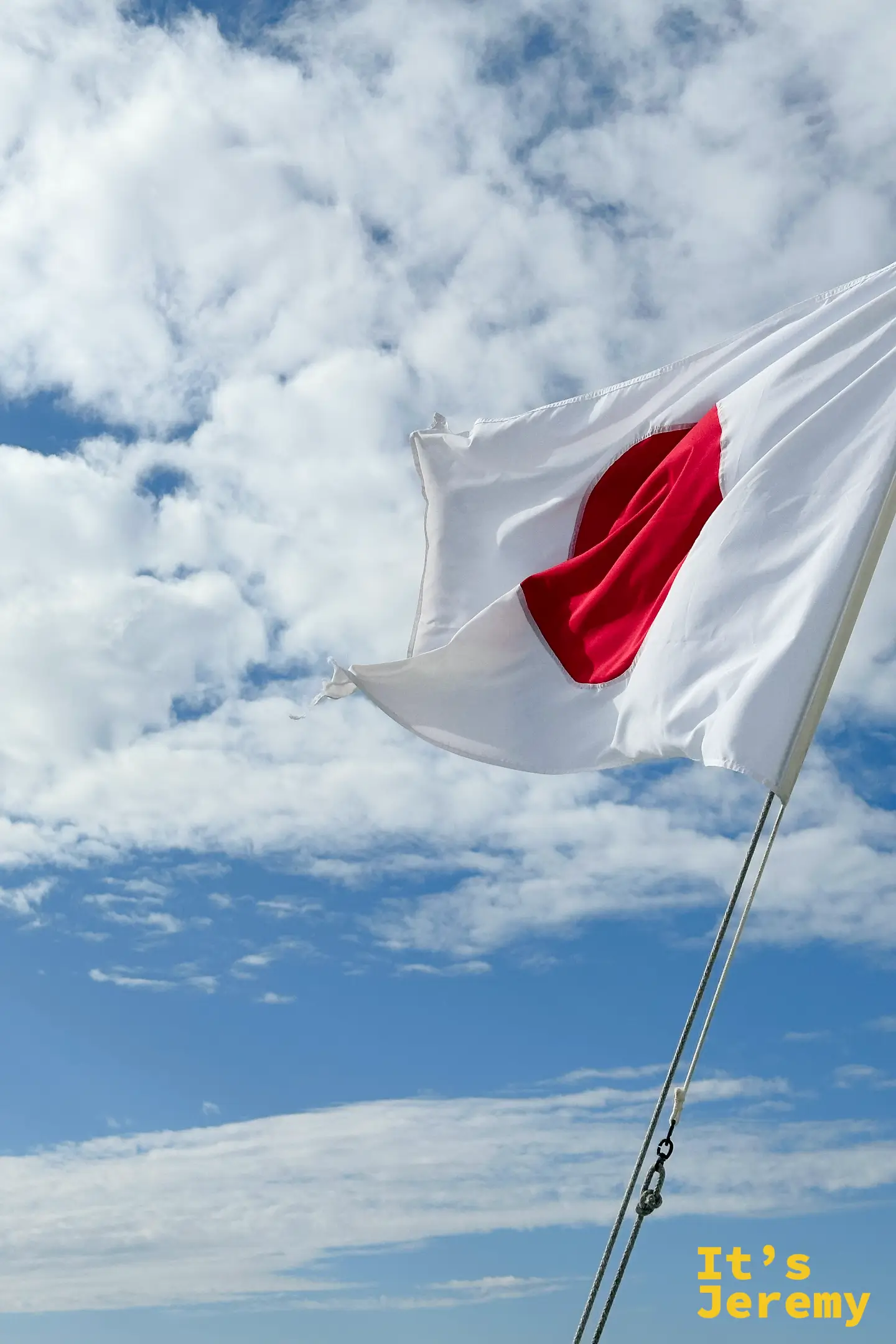 船尾的日本國旗在藍天白雲下迎風飄揚