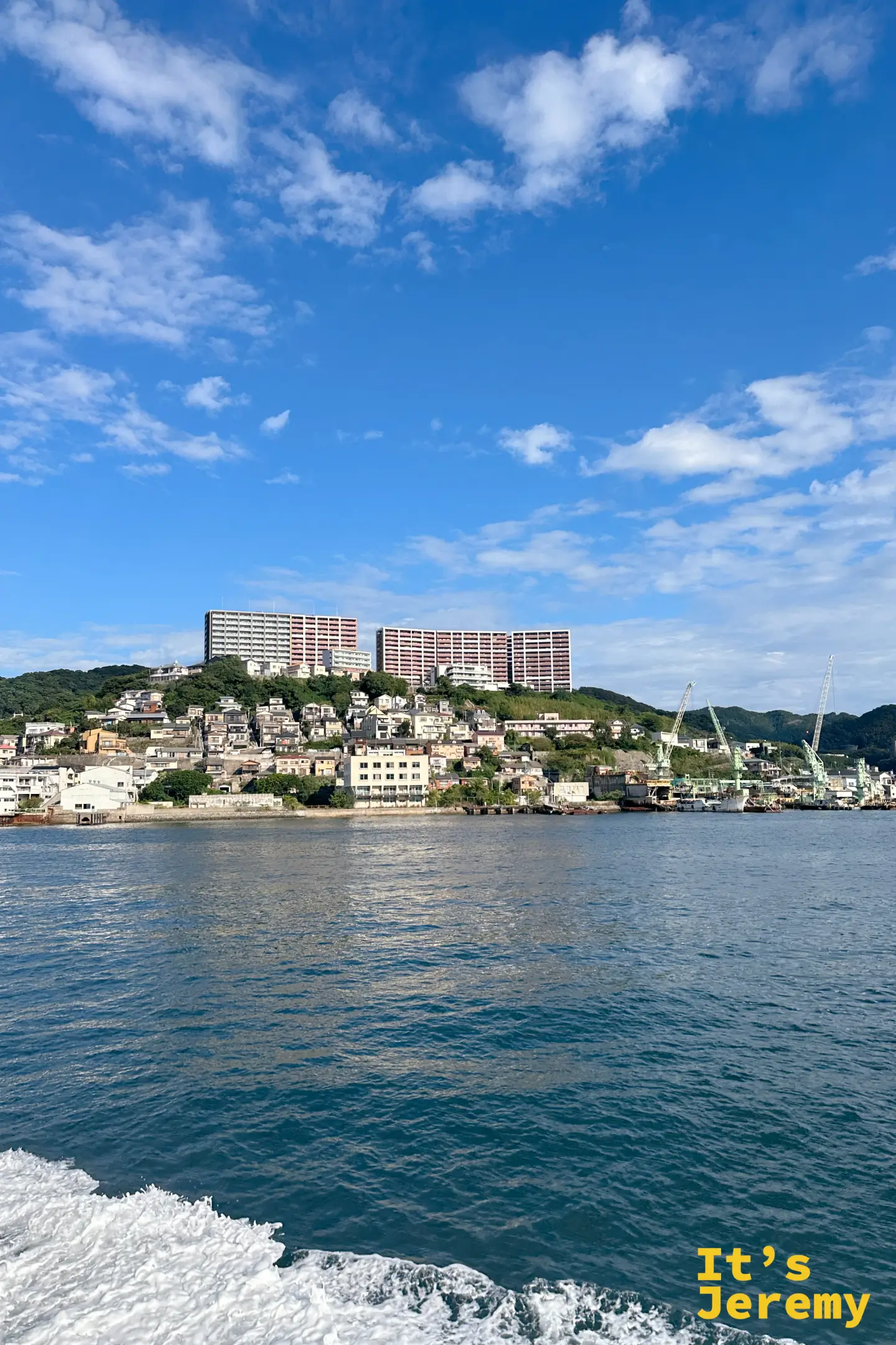 長崎典型的山坡地形，密集的住宅從海邊一路往上，山頂是兩棟長條狀的大型集合住宅