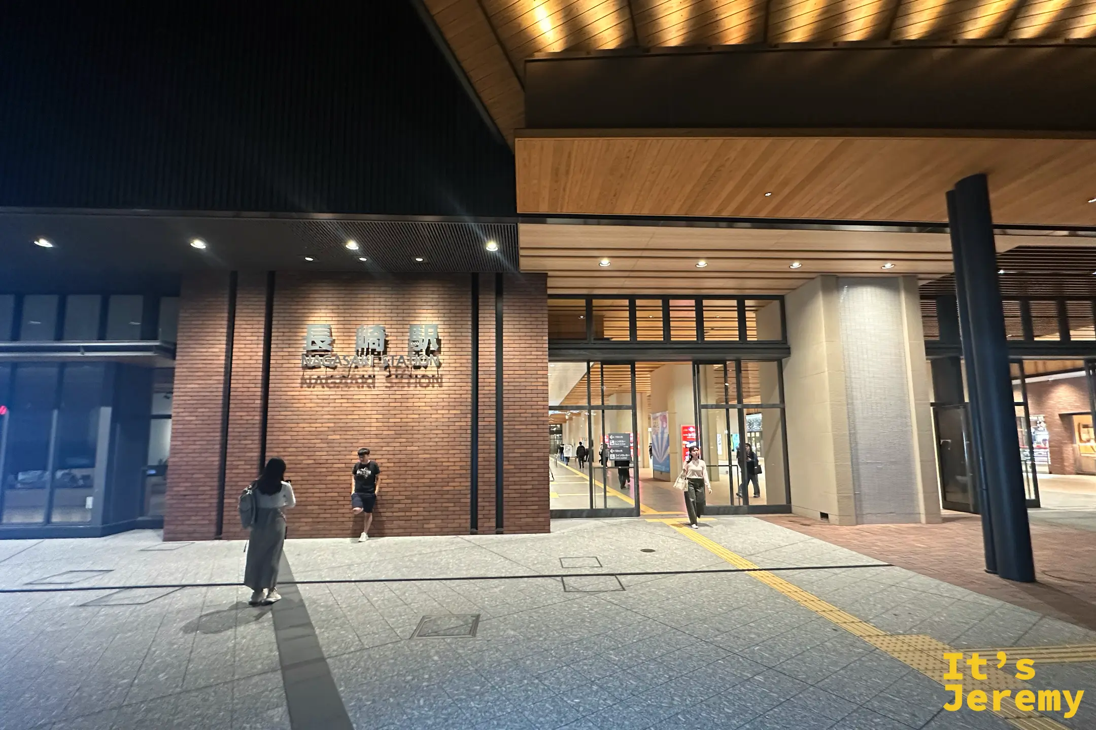 長崎車站入口，木質天篷與紅磚牆上的「長崎駅 NAGASAKI STATION」字樣，入夜後人來人往