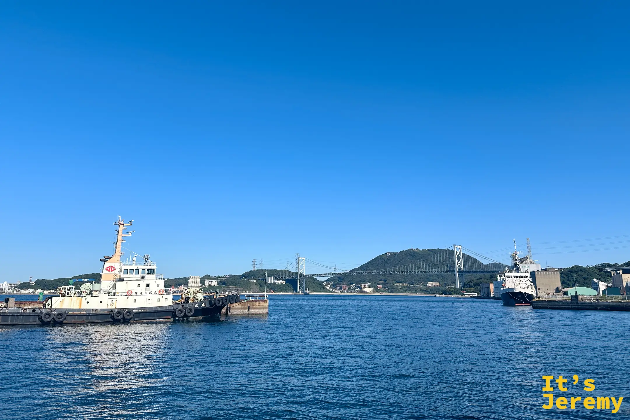 從門司港車站往海港方向遠眺,左側停靠著大型船隻與遠方的關門大橋,展現北九州門司港懷舊地區繁忙而充滿活力的海港景觀