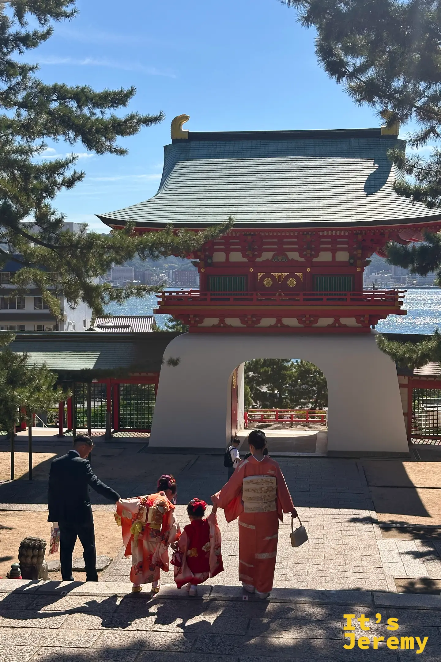 身著傳統和服的家庭走在下關赤間神宮境內,準備穿過水天門,背景可見關門海峽的海景