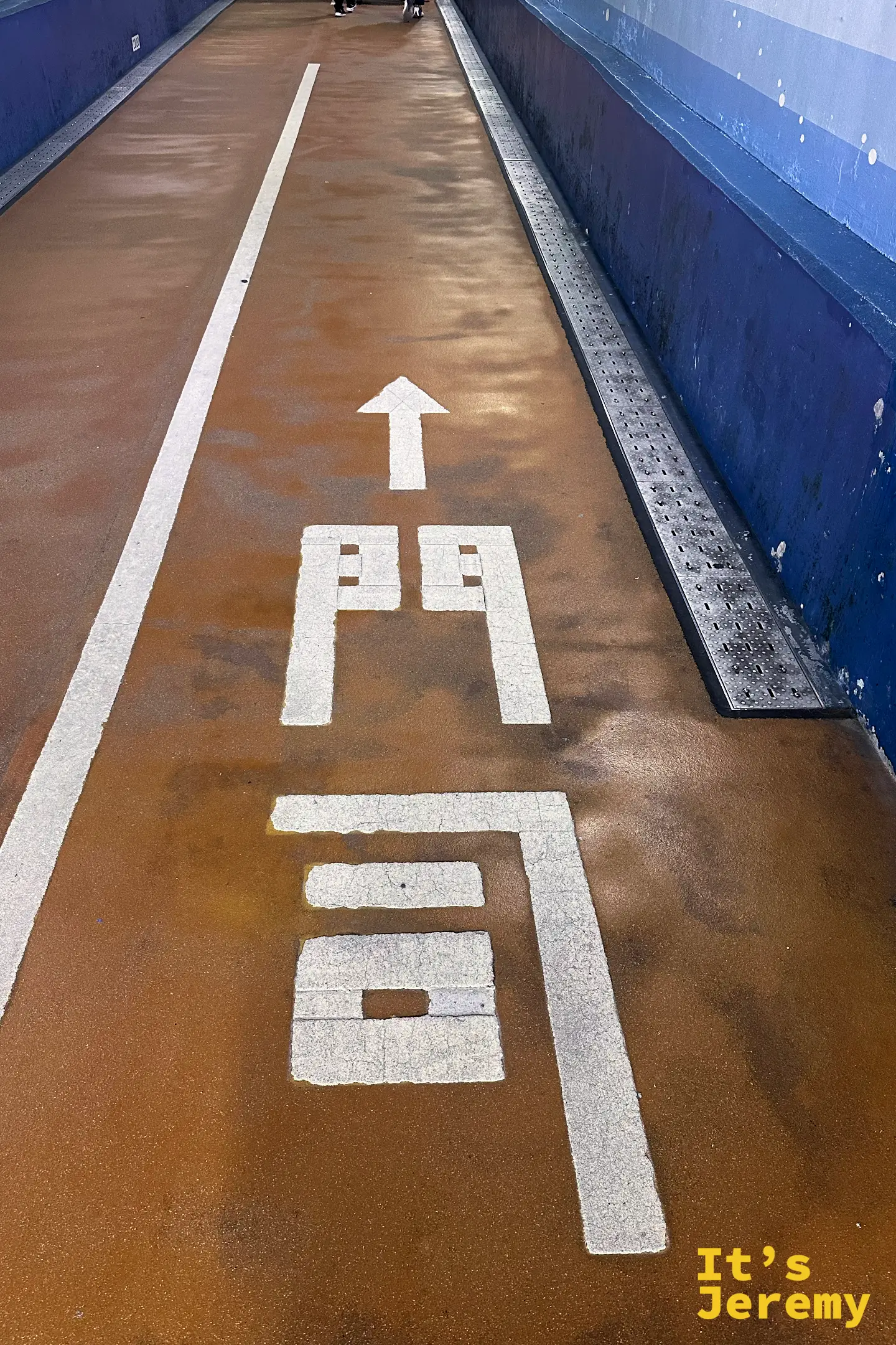 關門海底隧道步道地面指示特寫，箭頭指向福岡縣「門司」方向