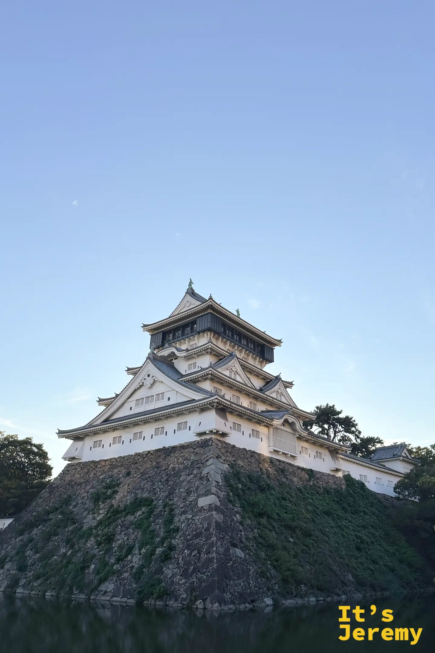 從小倉城公園遠眺天守閣的直式構圖，下方為靜謐的護城河水景，襯托出小倉城唐造式建築的宏偉姿態
