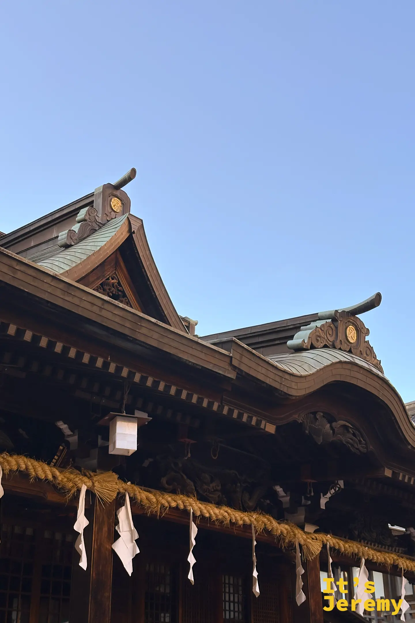 北九州小倉八阪神社神樂殿的屋頂結構特寫，展示日本傳統神社建築精湛的屋脊工藝與瓦片裝飾美學