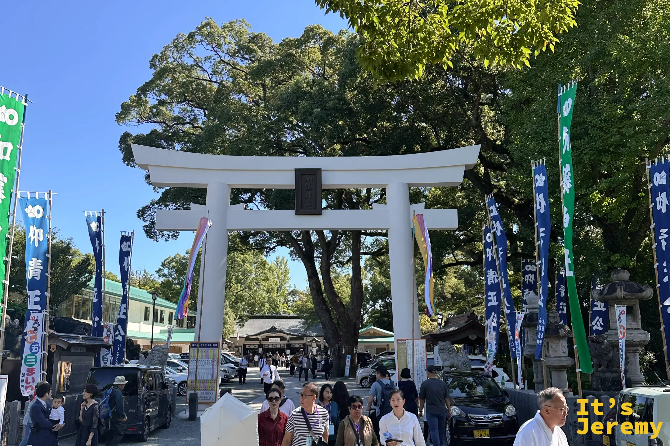 加藤神社大門鳥居與遊客,旁邊矗立著幟旗
