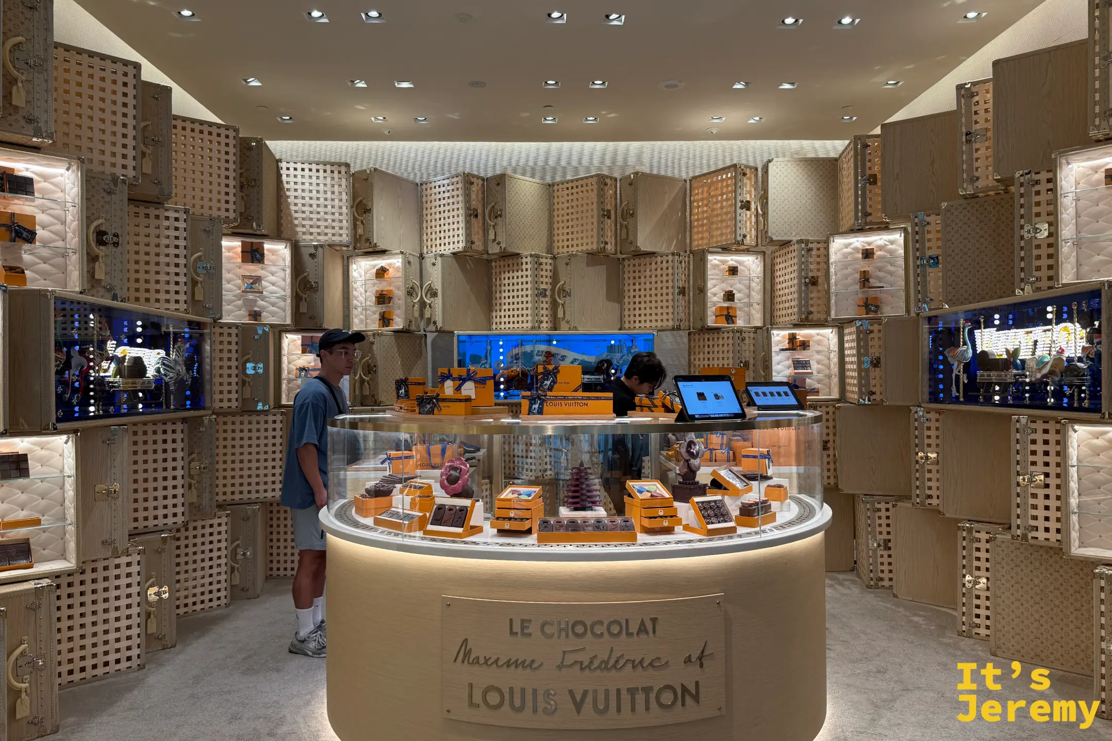 店內宏偉的環狀玻璃展示櫃印著店名，四周是仿 LV 皮件工坊的木質壓格牆面