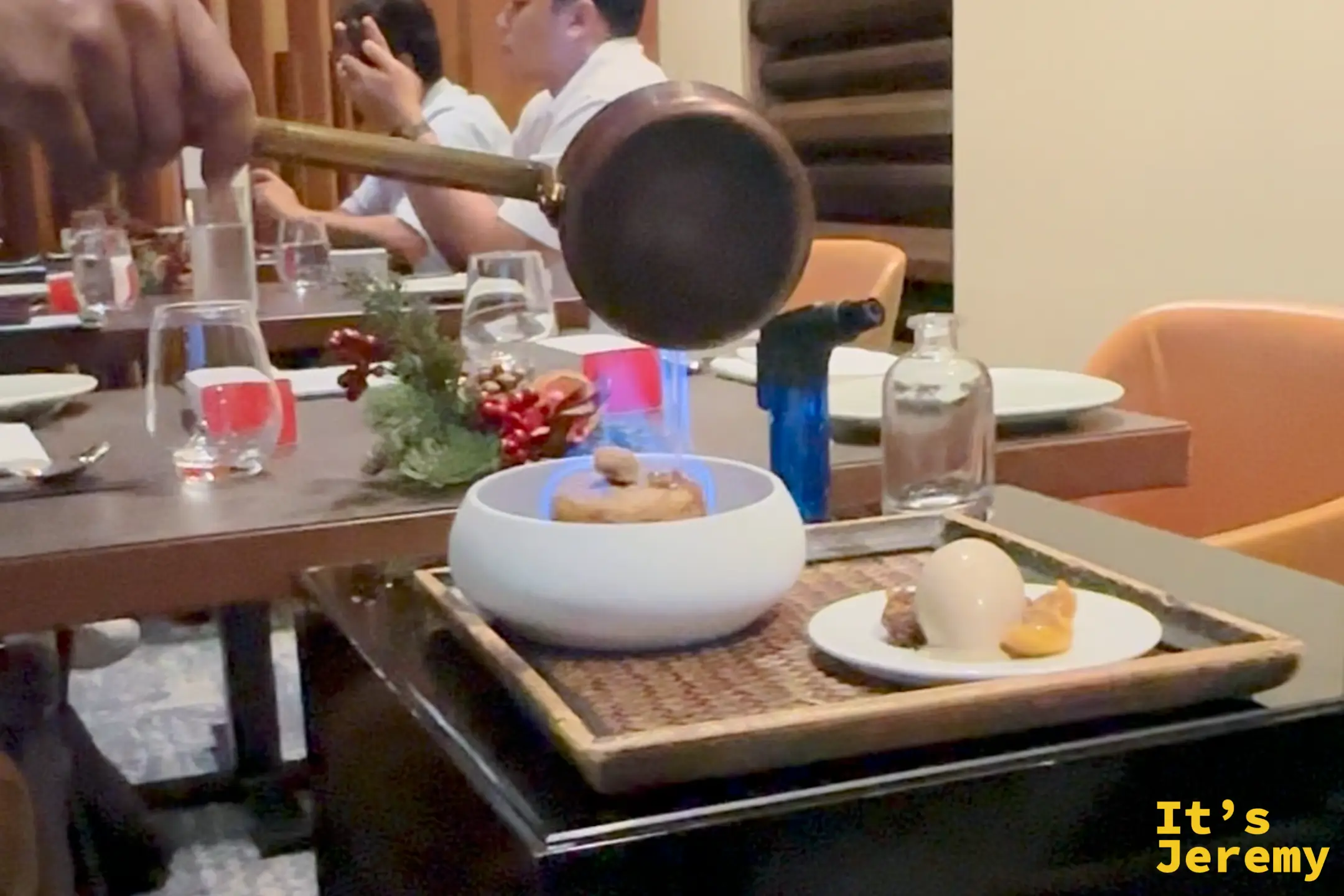 店員正在為 Osia 的招牌甜點澆酒點火，展現華麗的火焰表演