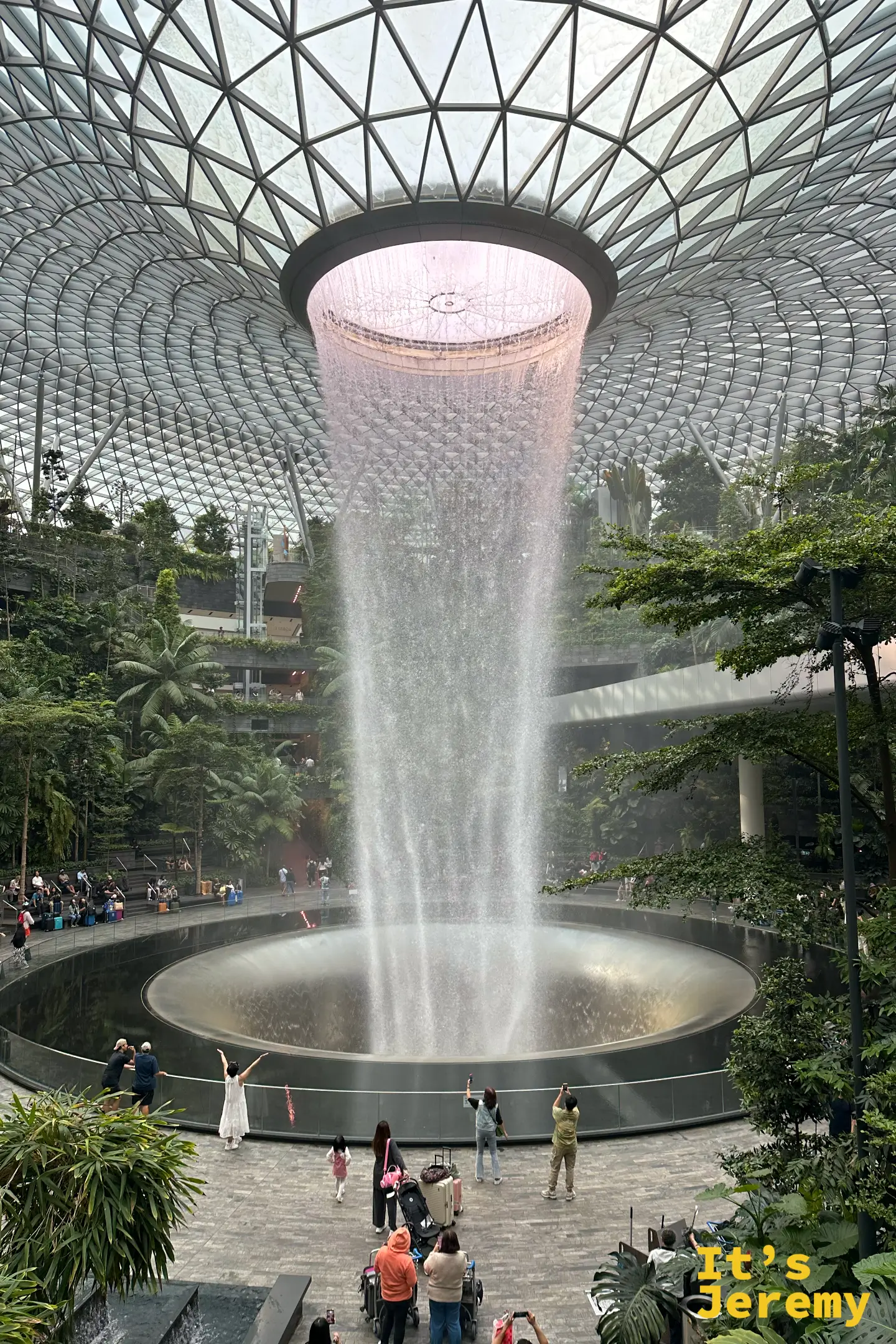 星耀樟宜雨漩渦,頂部圓形穹頂降下的水流在光影下呈現淡淡粉橘色