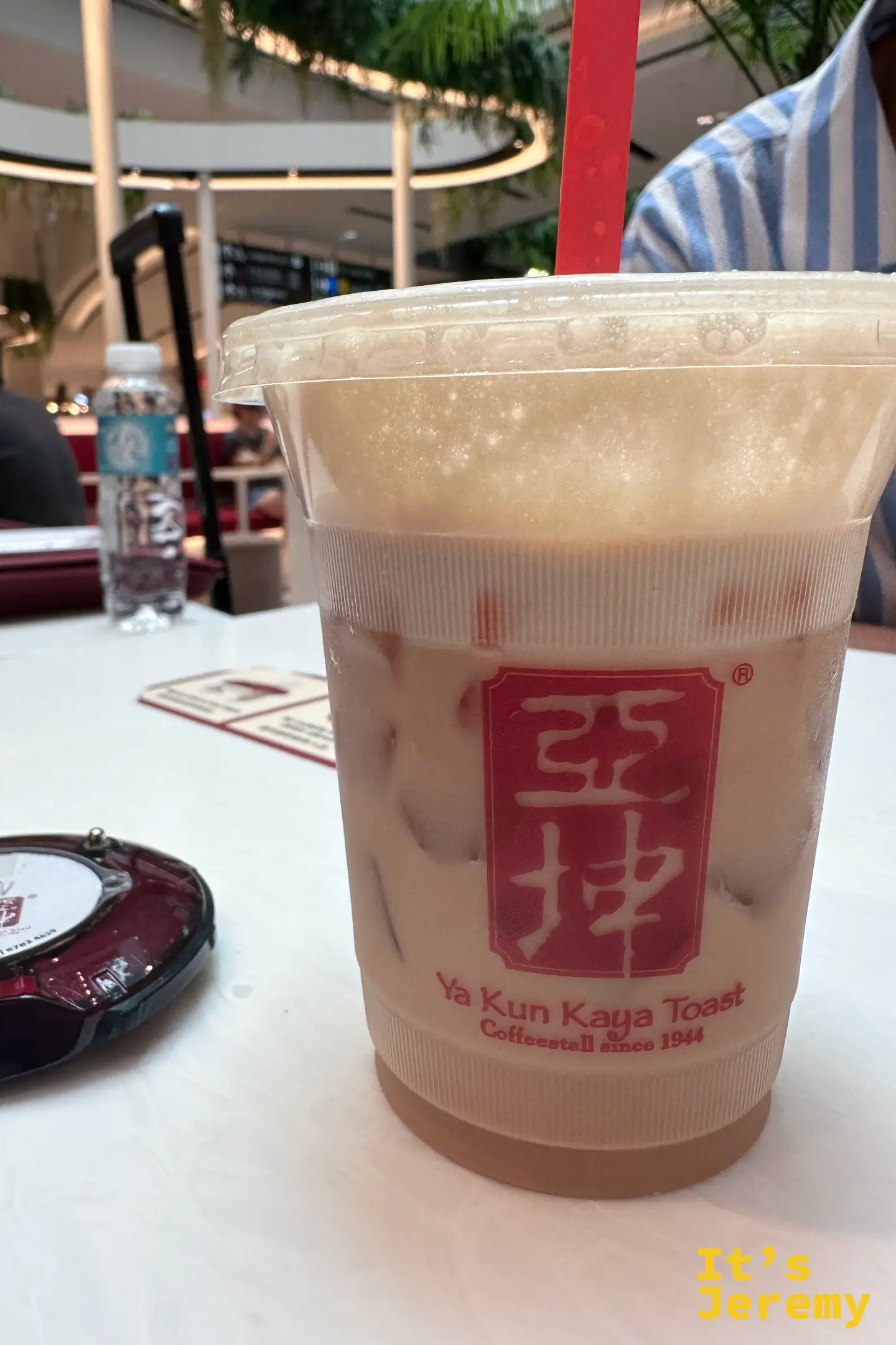 印有紅色「亞坤」標誌的冰絲襪奶茶特寫，頂部覆蓋綿密泡沫