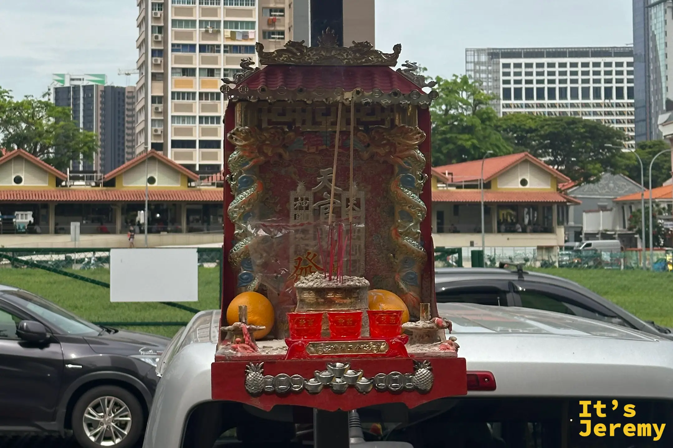 老街區柱子上綁著色彩鮮豔的紅色微型小神壇，下方擺著香爐與鳳梨供品