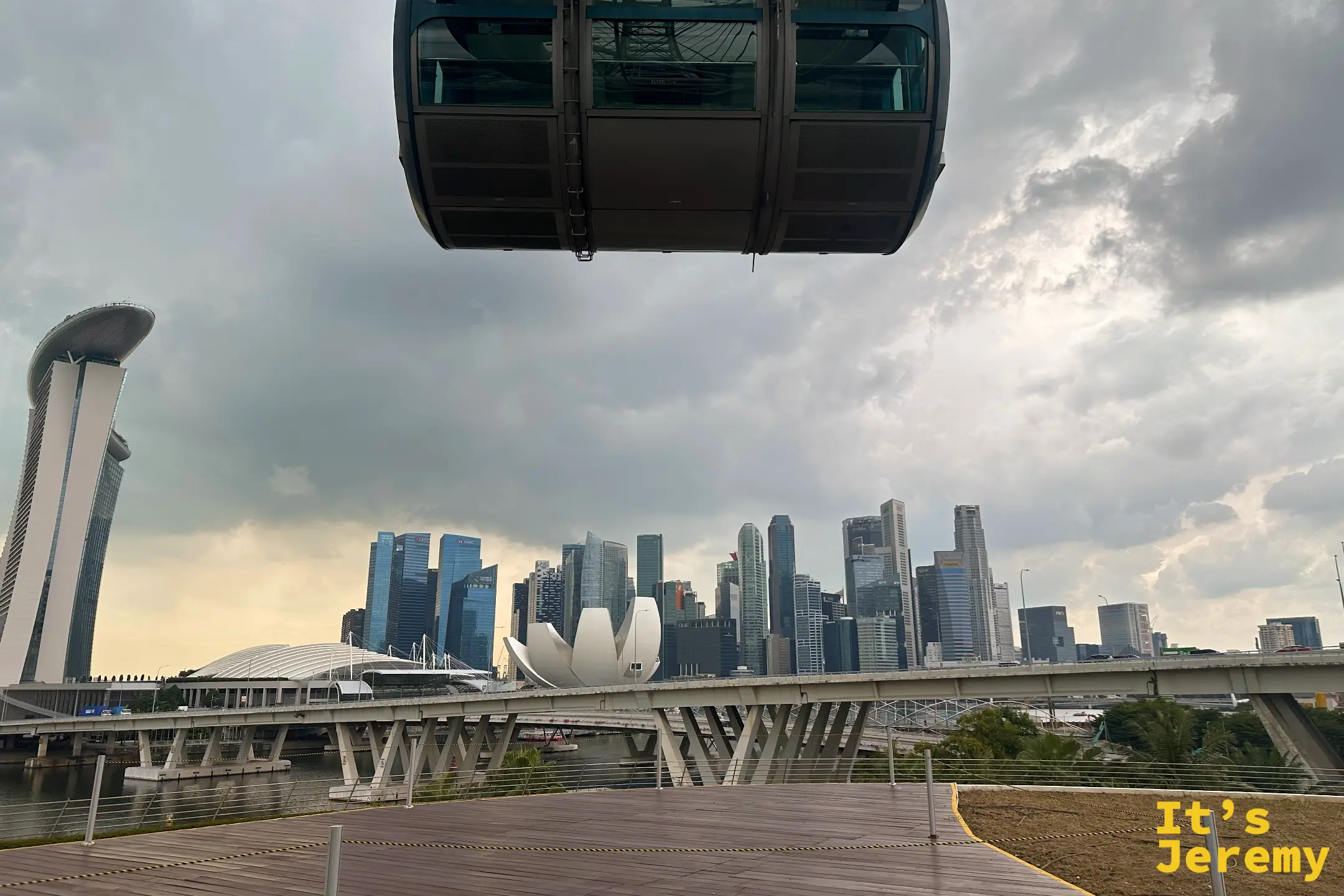 車廂外的巨大鋼骨輪軸結構,遠處是海濱大橋,天空多雲而開闊