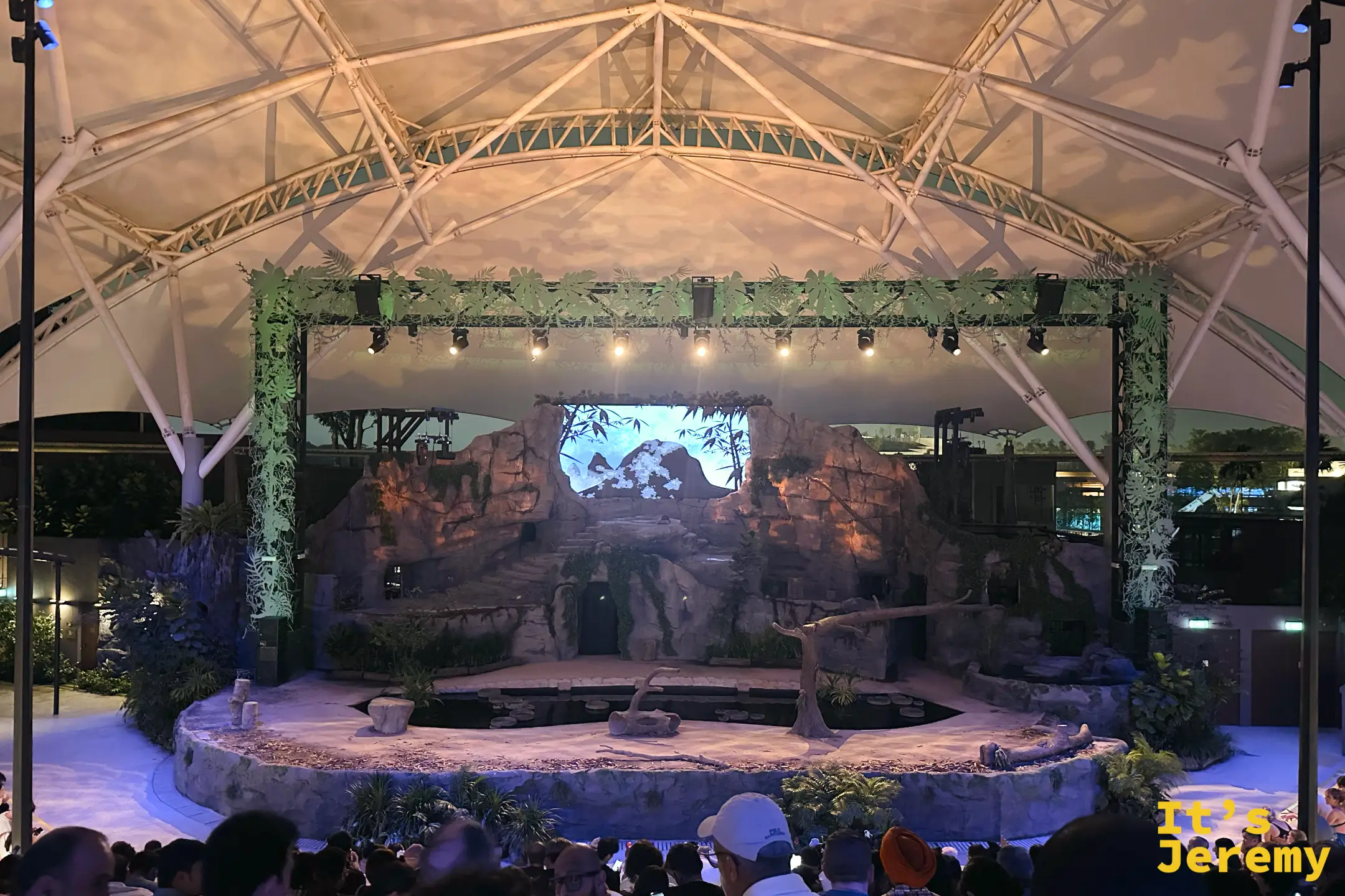 座無虛席的圓形劇場，遊客引頸期待夜晚精靈秀開演，上方是半球形薄膜棚頂
