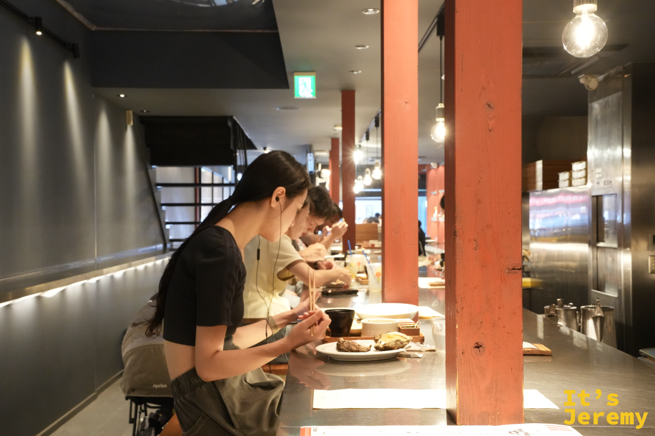 牡蠣屋店內，客人並排坐在長長的不鏽鋼吧台用餐