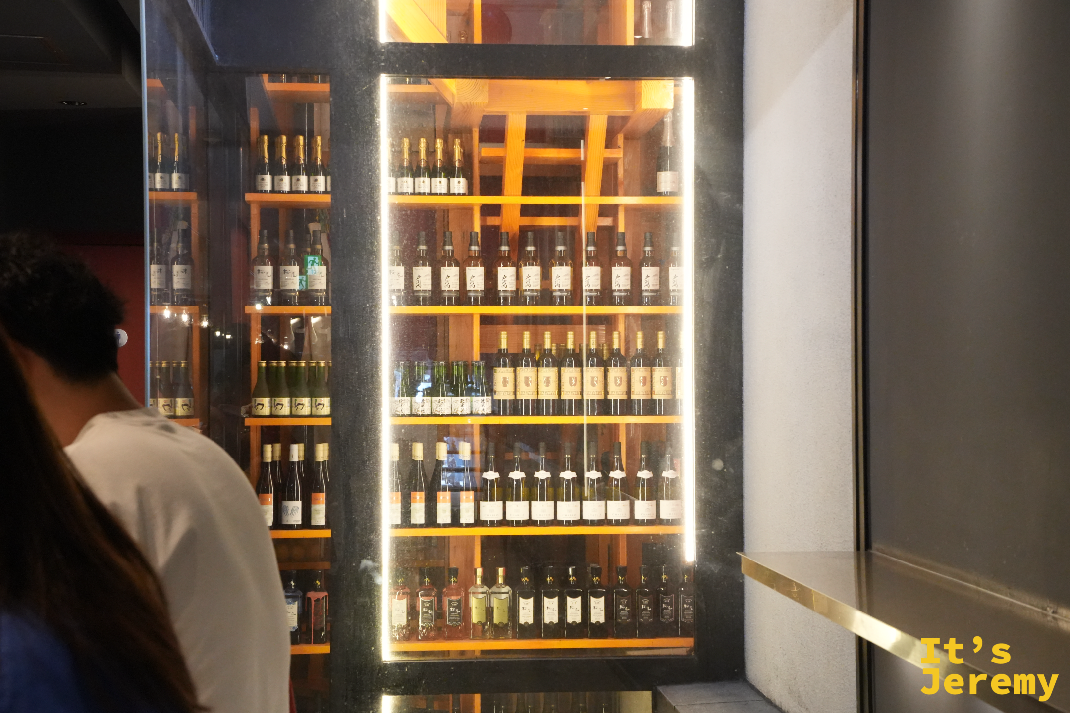 店內一整面發光的酒櫃，排滿香檳、白酒與清酒