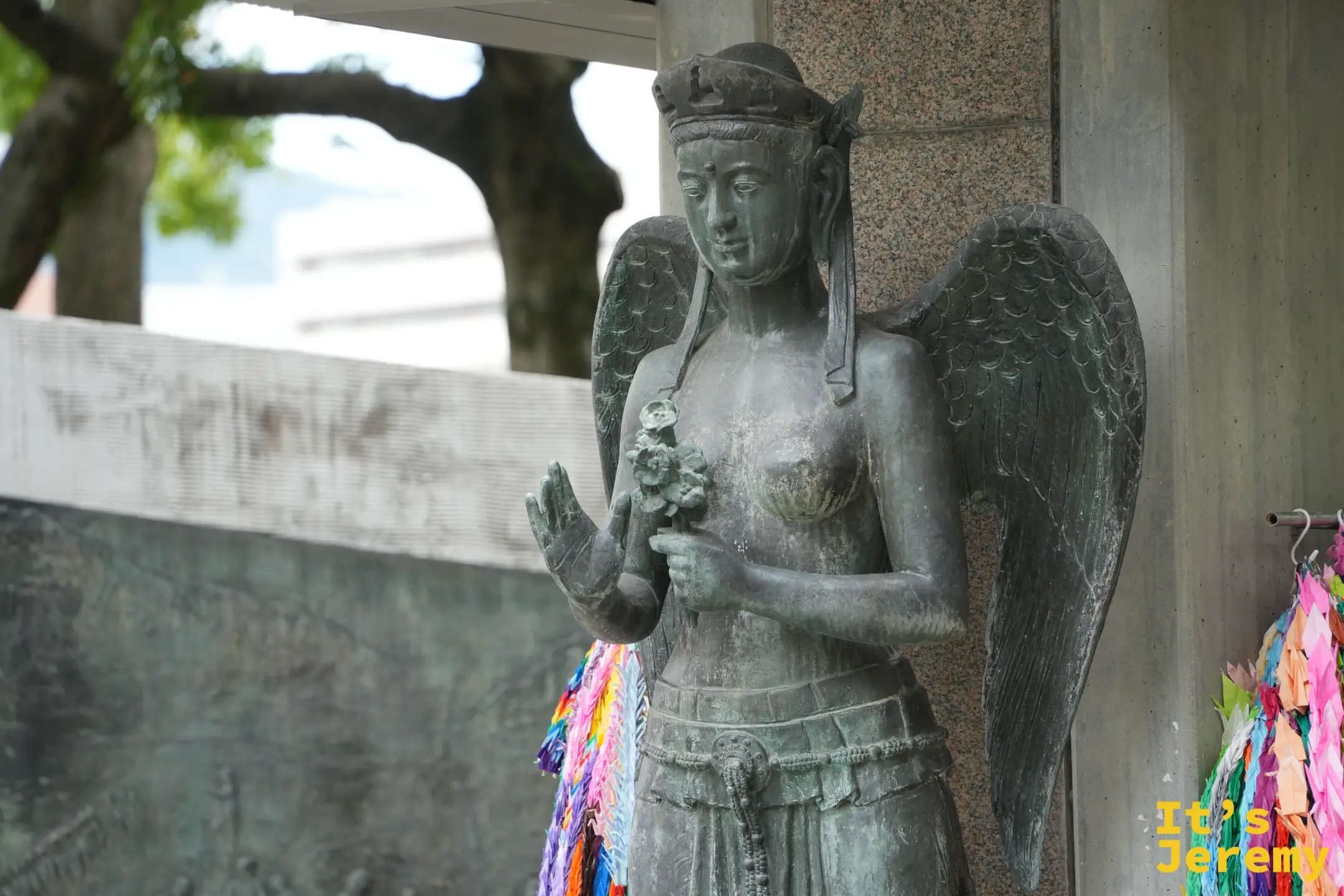 動員學徒慰靈塔的平和女神像，張開翅膀、手持花朵，旁邊掛著千羽鶴