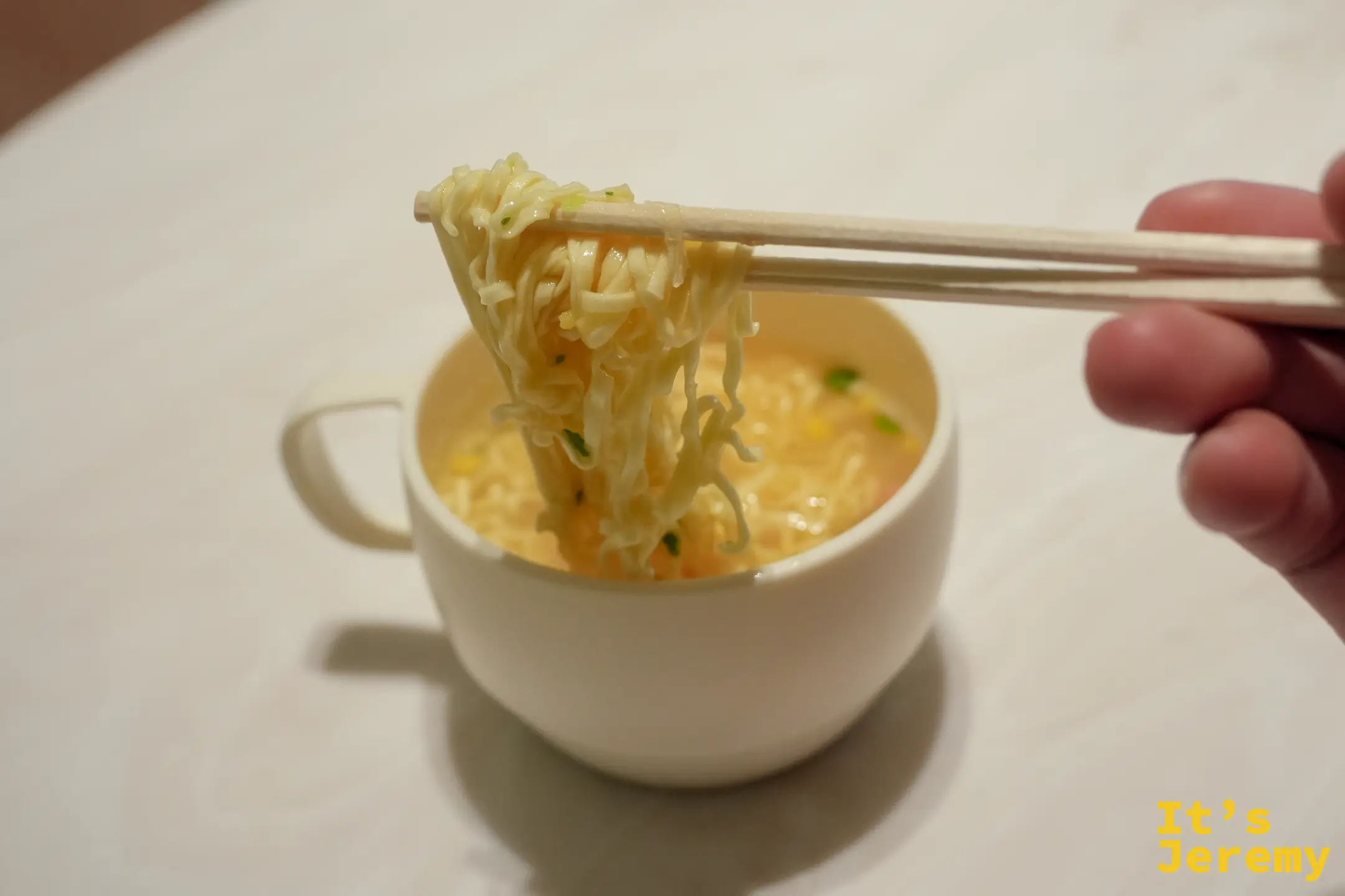 用筷子夾起馬克杯裡的海鮮杯麵